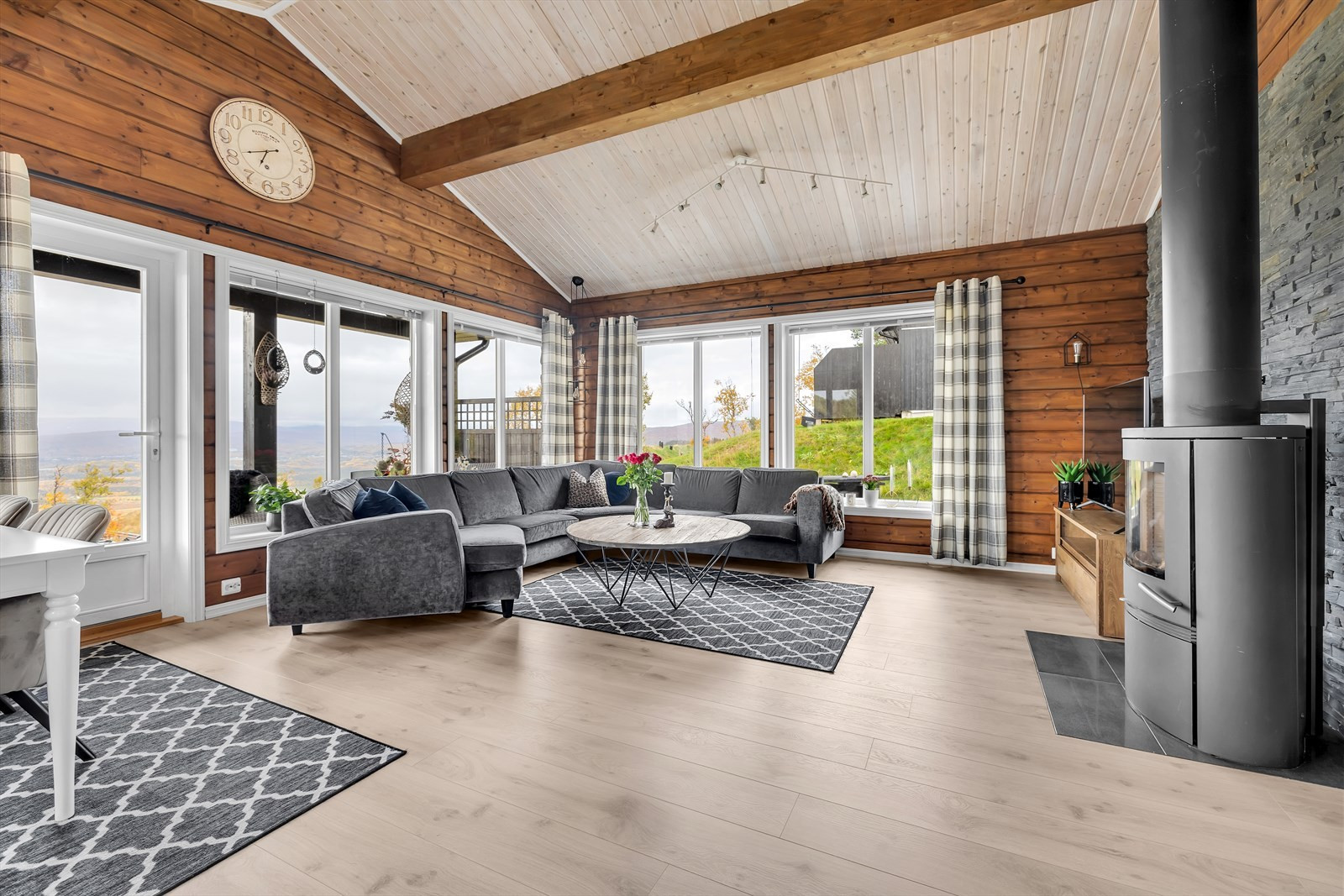 Nydelig åpen stue med store vindusflater og høyt under taket.