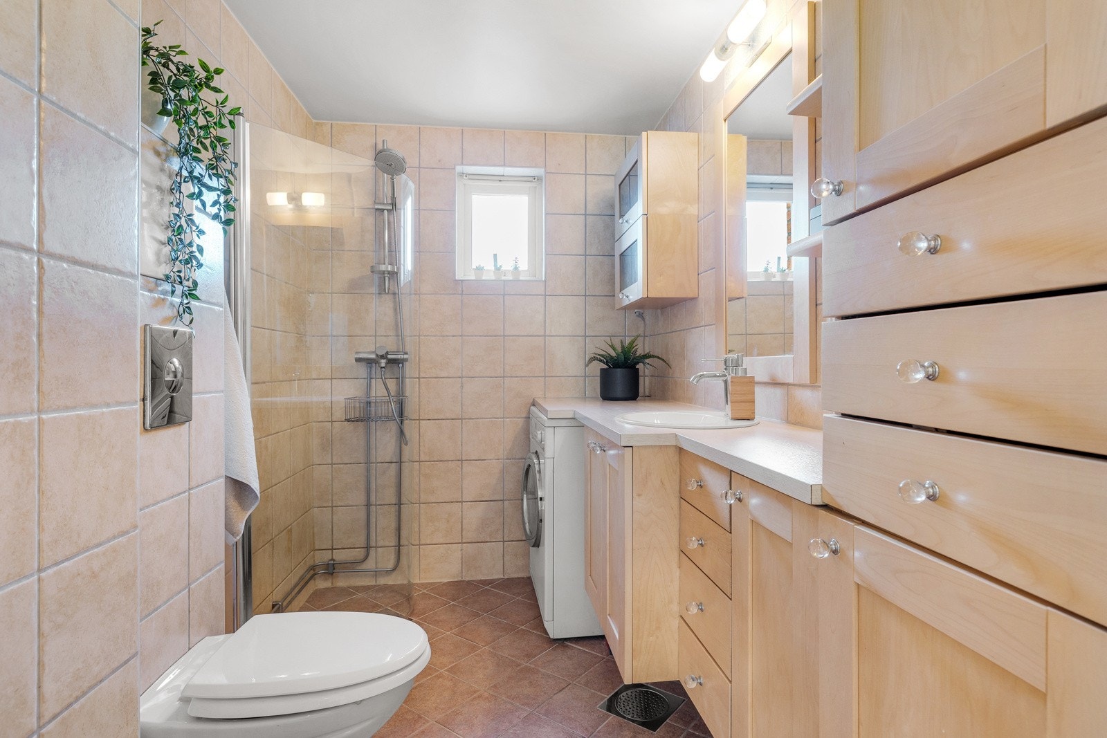 Stort flislagt baderom med opplegg for vaskemaskin. Galleribilde