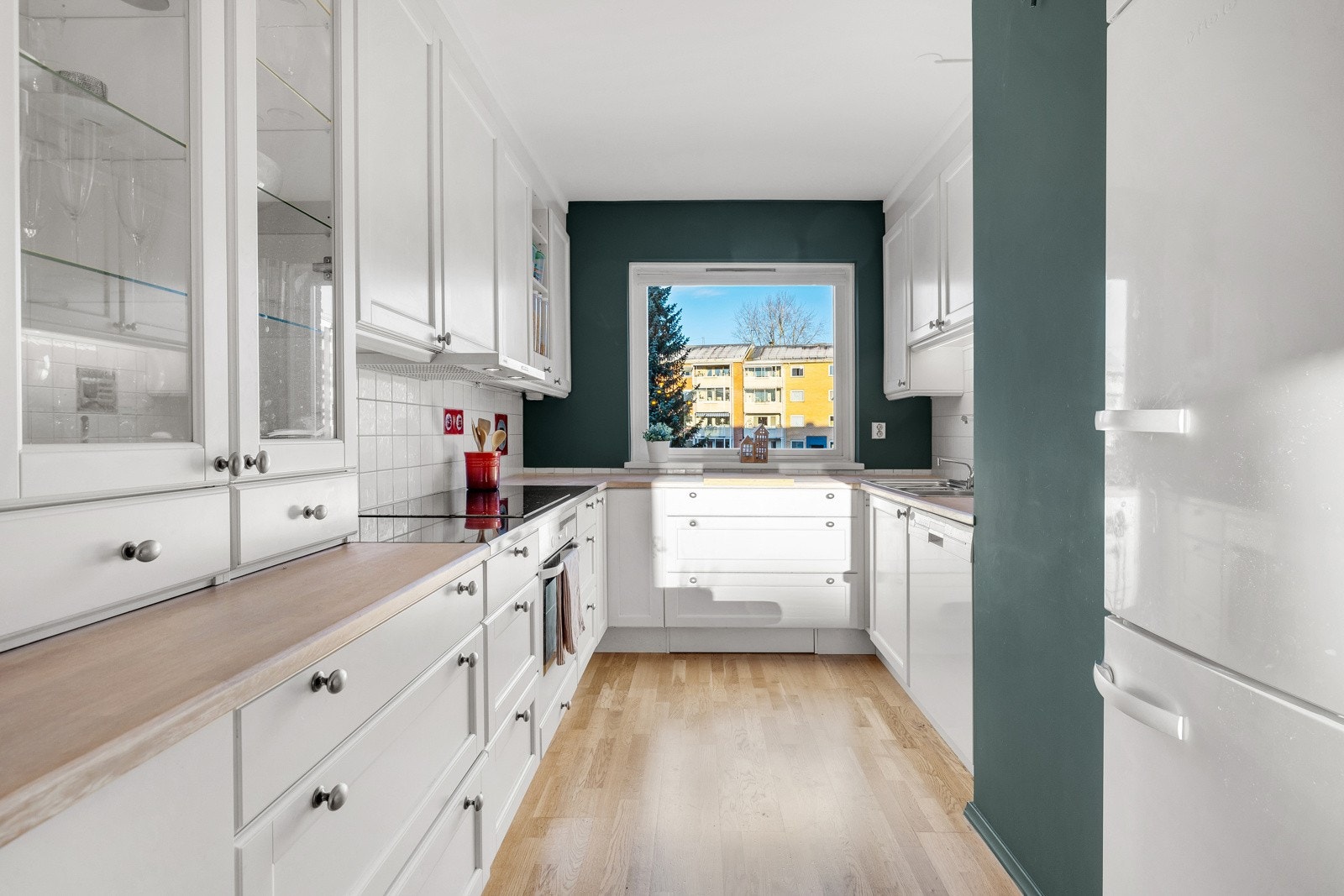 Kjøkkeninnredningen har et tidsriktig uttrykk med hvite profilerte fronter og heltre benkeplate. Galleribilde