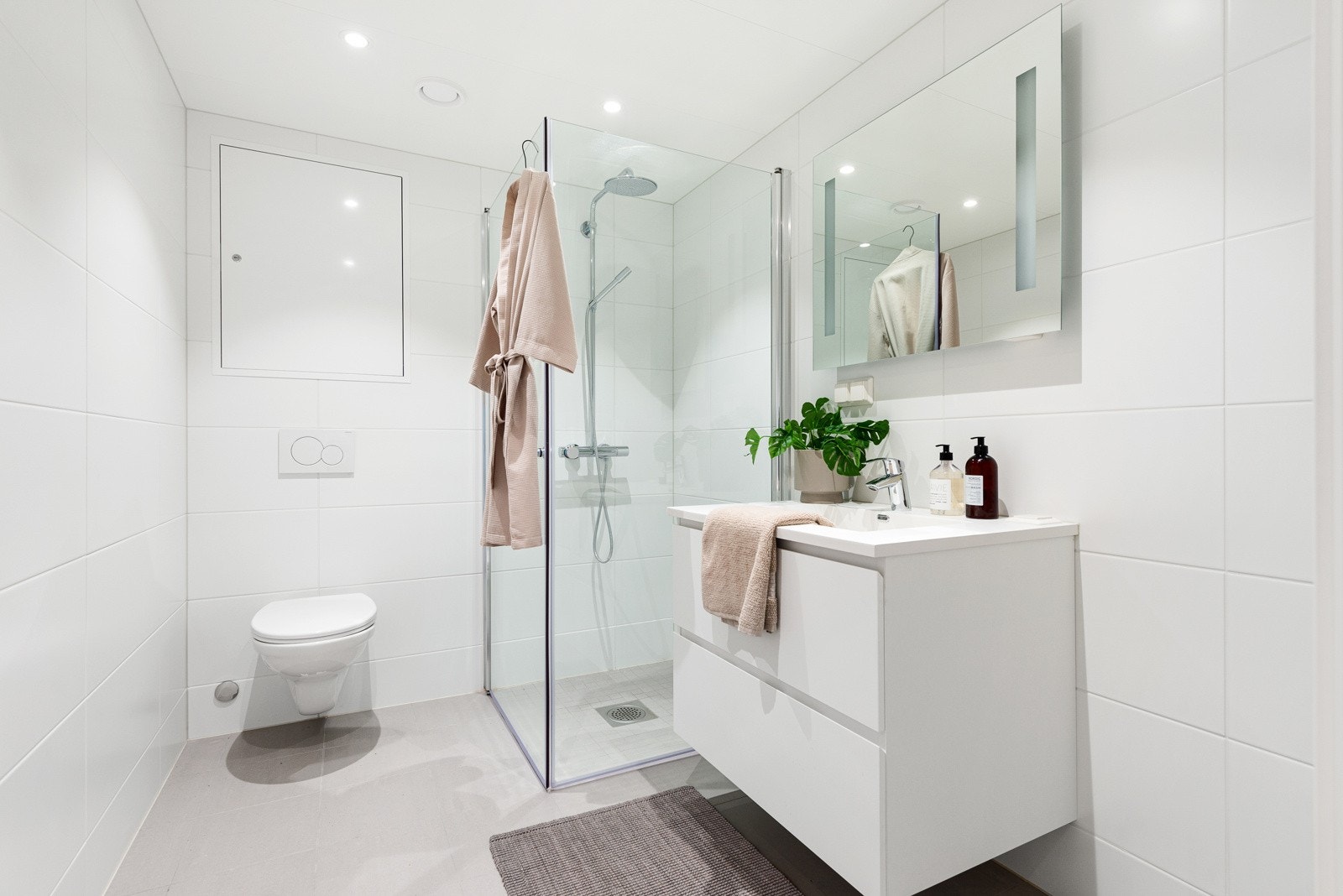 Lekkert baderom med flislagte flater, gulvvarme, vegghengt wc, downlights og opplegg for vaskemaskin. Galleribilde