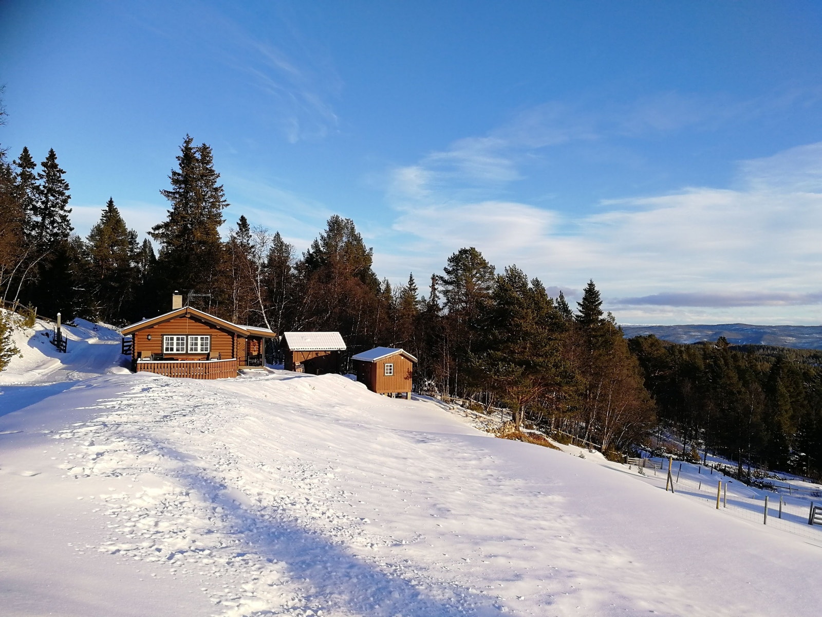 Tømmerhytta ligger høyt og fritt med gode solforhold og utsikt utover dalen og fjellene omkring. Bildet tatt februar 2022. Galleribilde