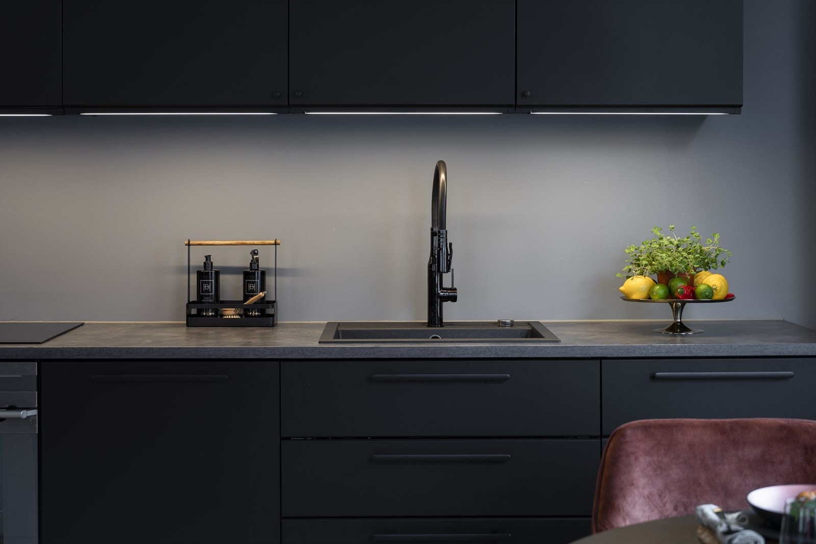 Kjøkkeninnredning med sorte glatte fronter og laminert benkeplate. Benkeskapsbelysning og stikkontakter. Nedfelt oppvaskkum av kompositt med ett-greps armatur Galleribilde