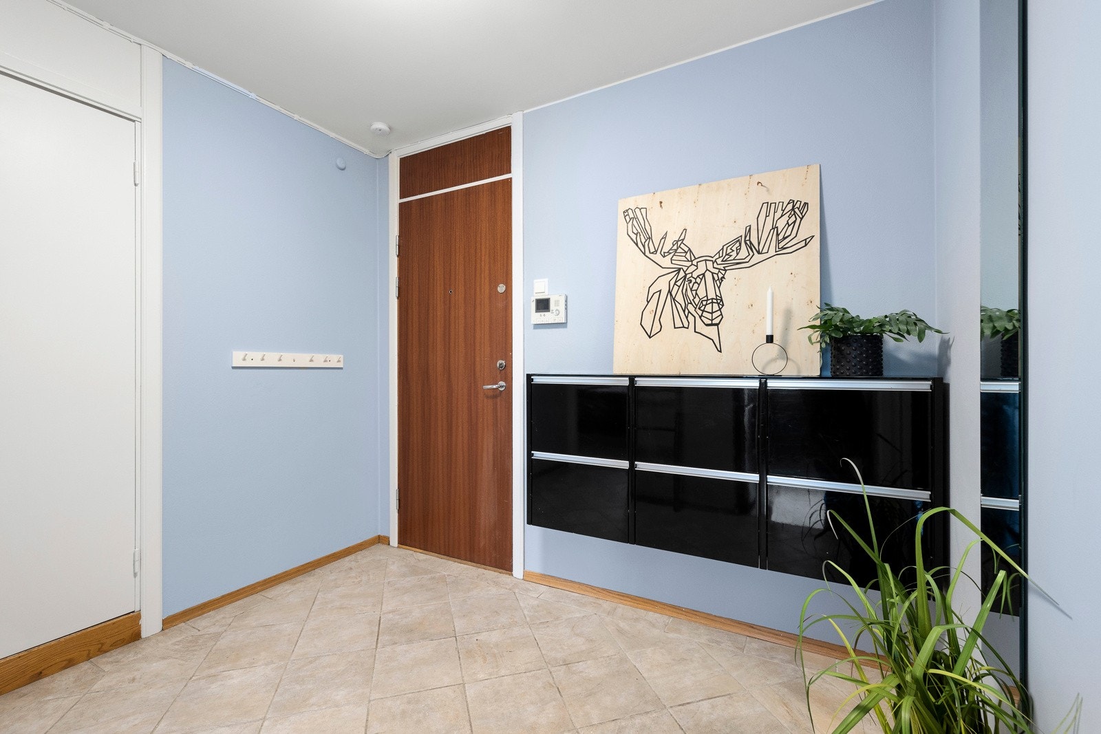 Vel inne blir vi ønsket velkommen i en pen entré med fliser på gulvet, og plass til knaggrekker og skoskap Galleribilde