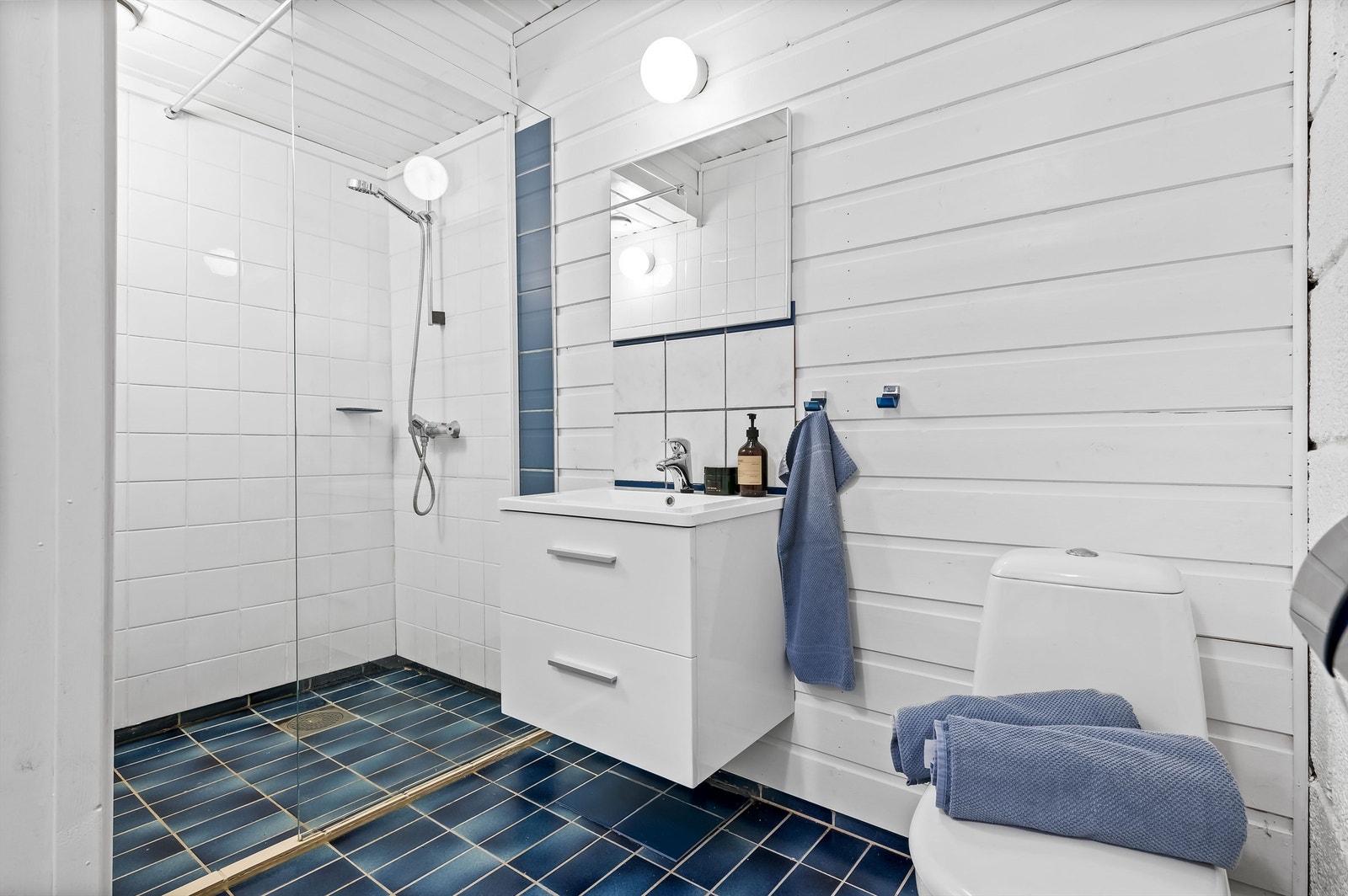 Bad i kjeller med toalett, servant, servantinnredning og dusjnisje Galleribilde