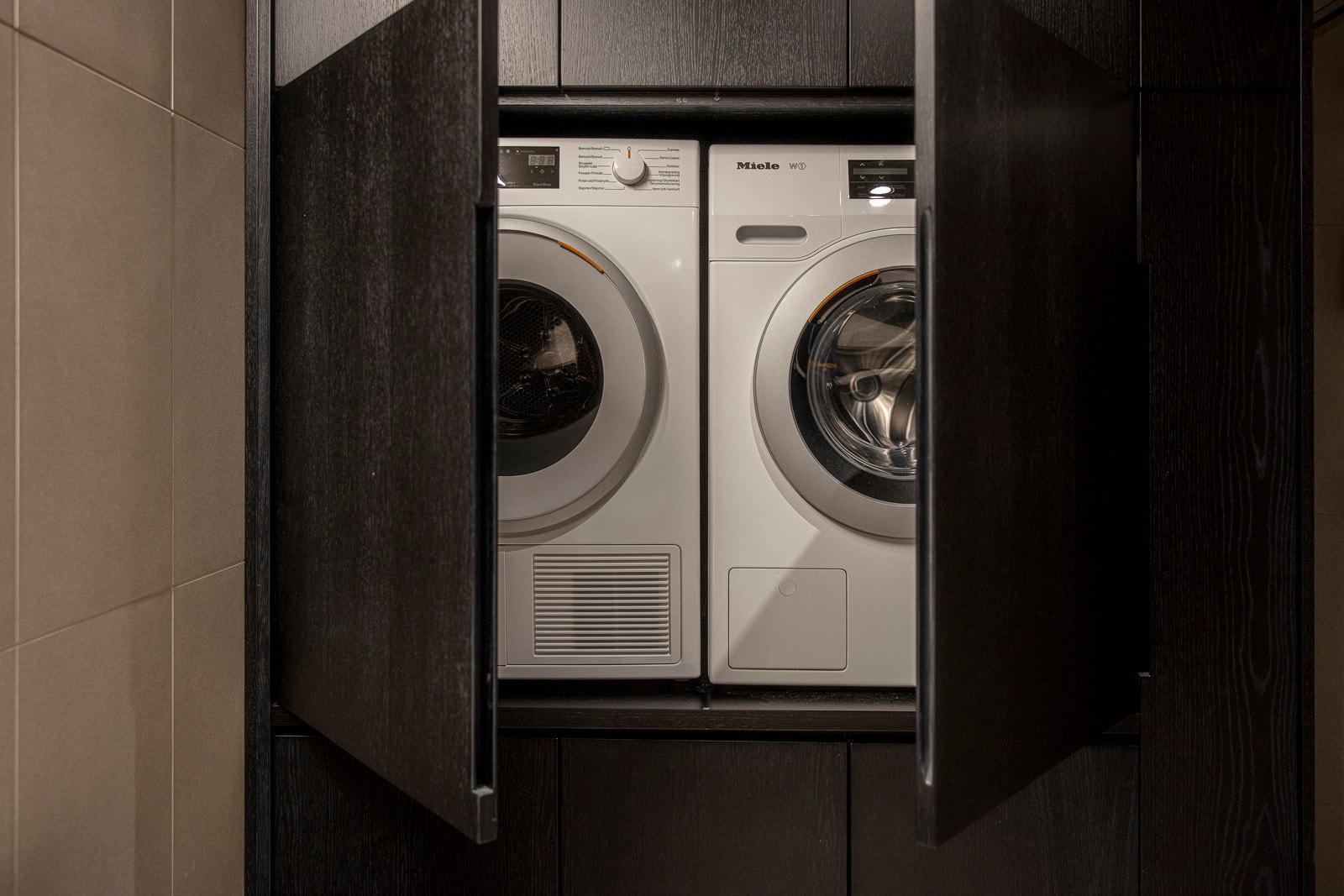 Badet har en spesialtilpasset skapinnredning fra gulv til himling i mørkbeiset eik. Her er det plass for vaskemaskin og tørketrommel. Galleribilde