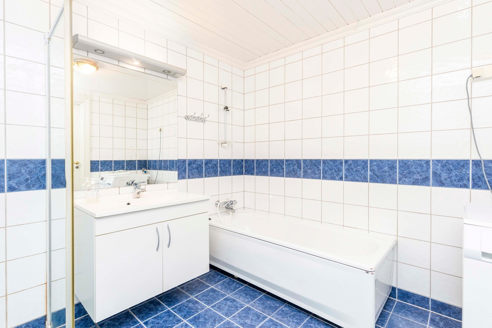 Badet er innredet med dusj, badekar, servant med underskaper og toalett. Opplegg til vaskemaskin. Varmekabler i gulv. Galleribilde