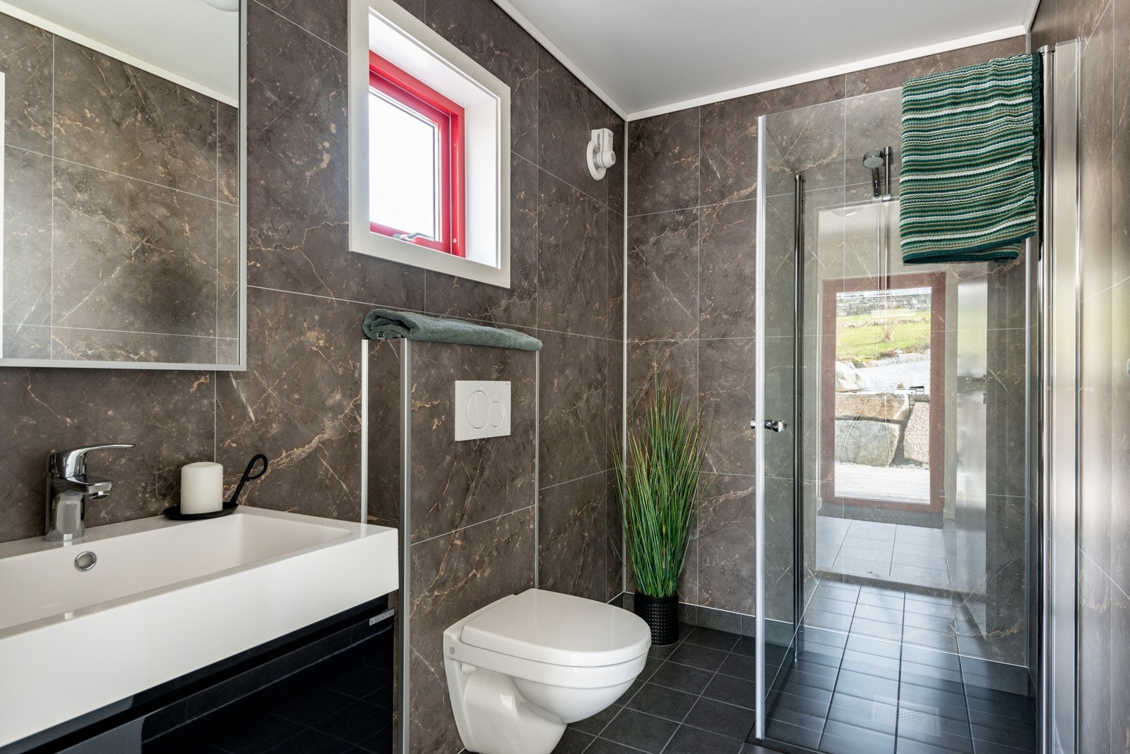 Badet i 1.etasje. Det er inngang til badet frå entréen. Lekkert bad med toalett, servant og dusj. Bilete frå Strandhus 2 Galleribilde