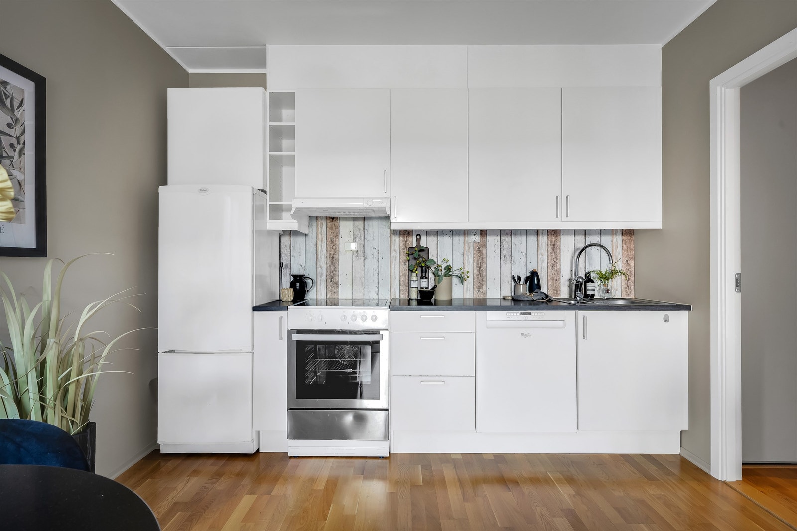 Innredningen har hvite fronter og godt med skap- og benkeplass. Benkeplaten er i laminat, og har rustfri oppvaskkum og ettgreps armatur. Videre er det frittstående hvitevarer som stekeovn, kjøleskap og oppvaskmaskin. Galleribilde