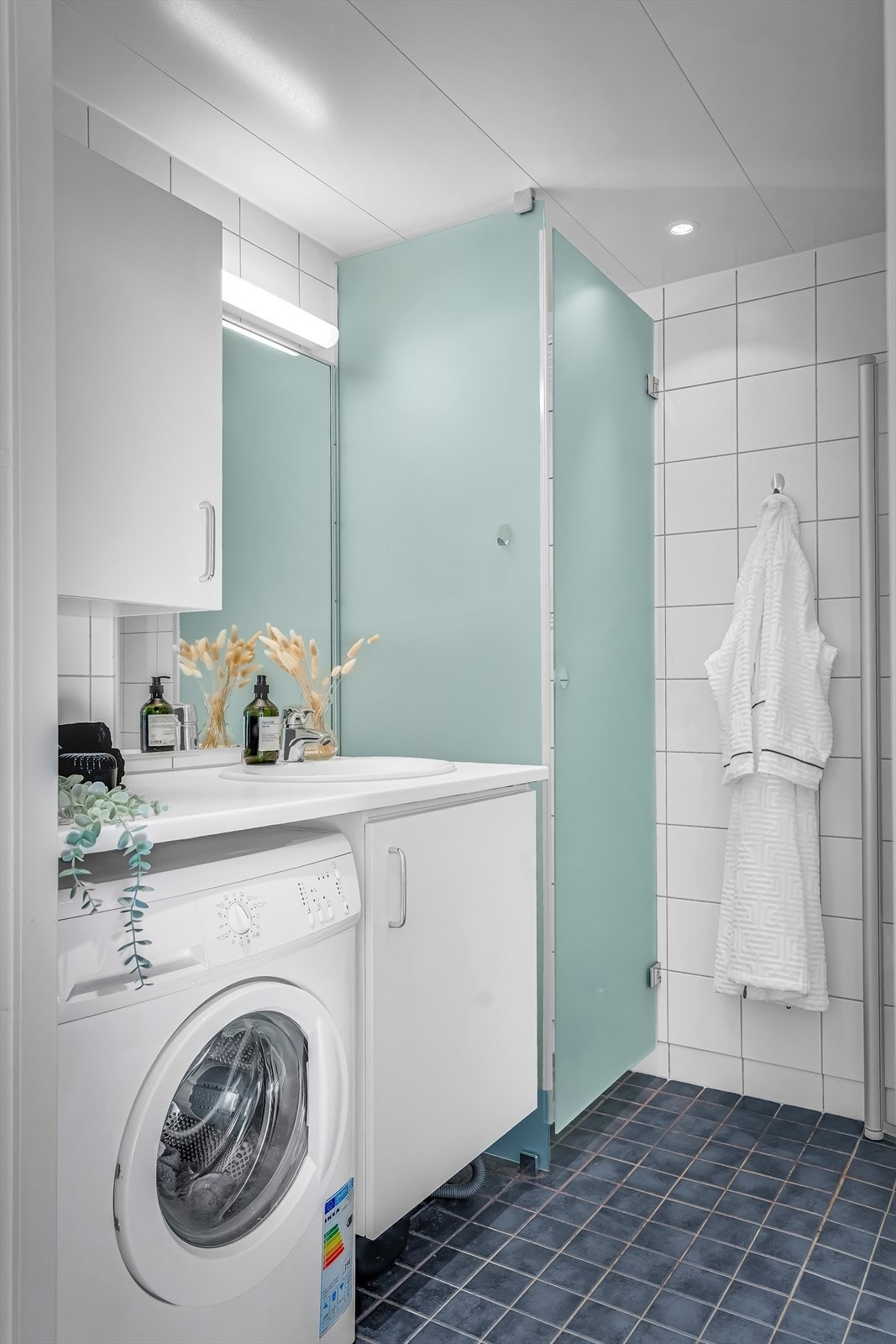 Badet er utstyrt med vegghengt toalett og dusjhjørne med innfellbare glassdører i herdet glass. Galleribilde