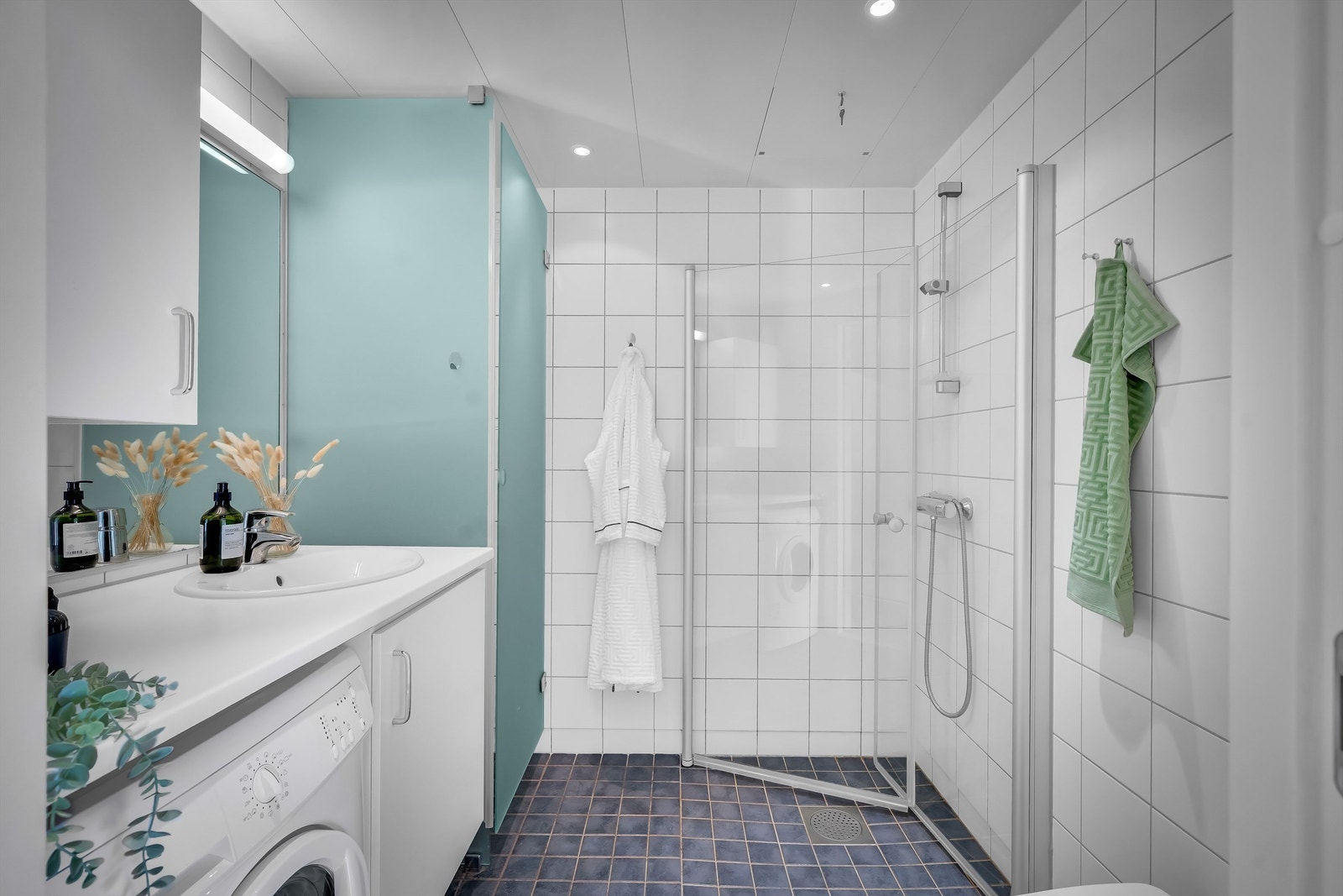 Innbydende bad med hvite fliser på vegg, gråmelerte fliser med varme i gulv og downlights i himling. Galleribilde