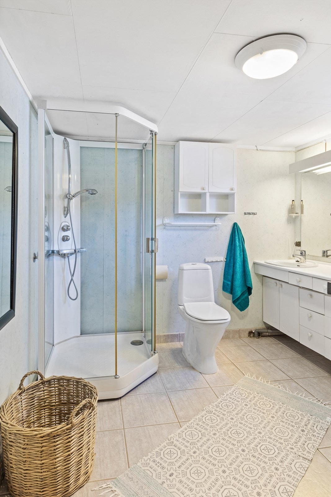 Badet er av god størrelse med flislagt gulv, dusjkabinett og servantinnredning. Galleribilde