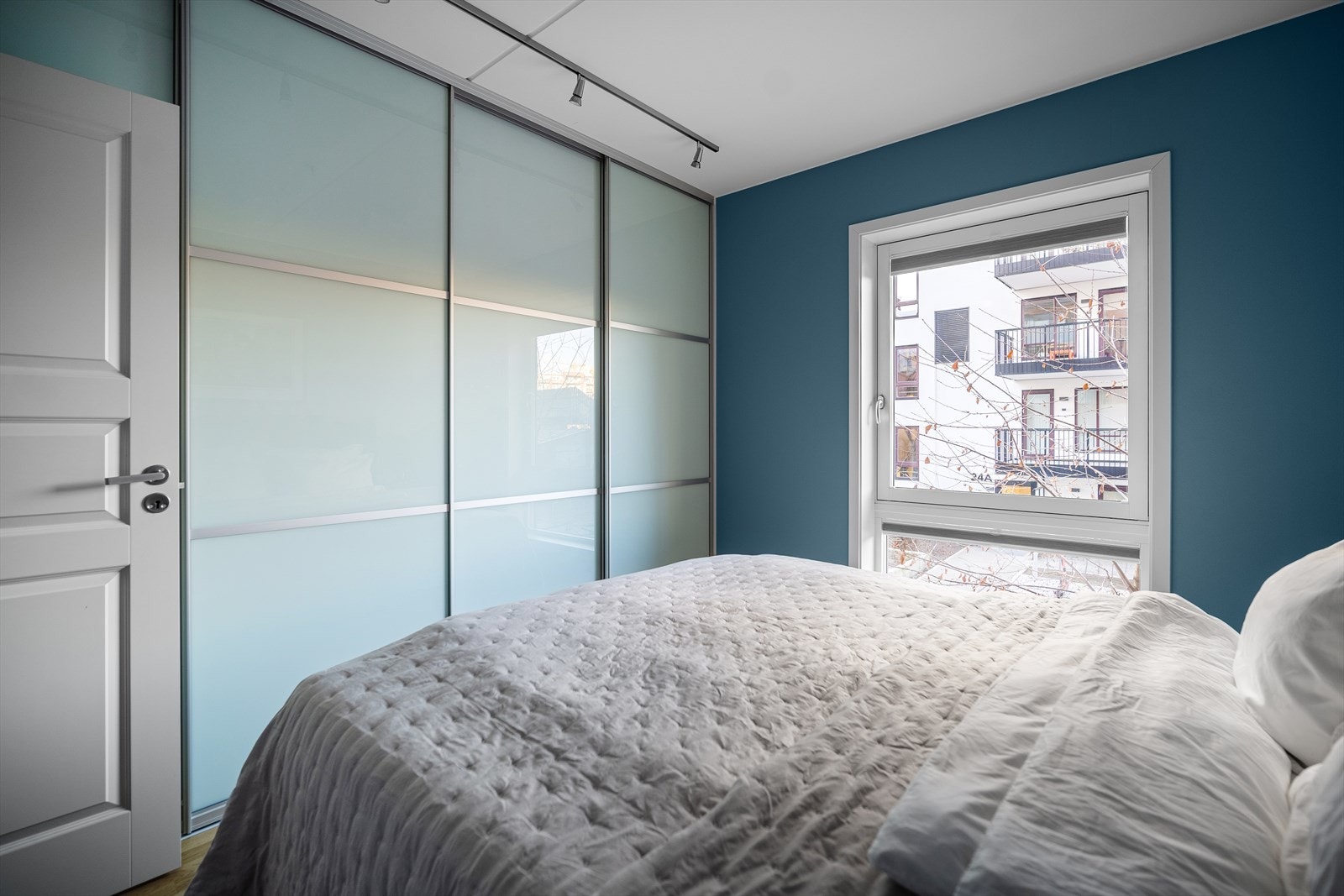 Langs den ene veggen er det montert en stor skyvedørsgarderobe med belysning over. Galleribilde