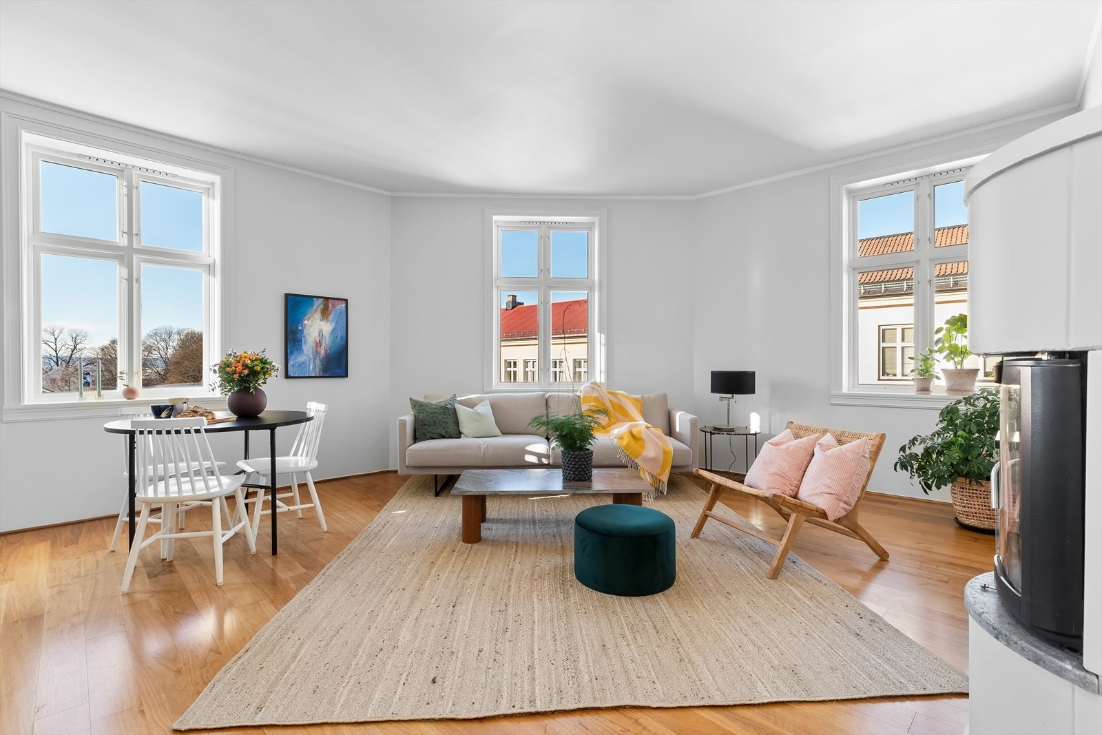 Utformingen av stuen gjør at rommet føles omfavnende og de store vinduene slipper ettermiddagens solstråler inn slik at leiligheten bader i lilla, oransje og rosa toner samtidig som du kan åpne dem og nyte at det er stille og rolig utenfor. Galleribilde