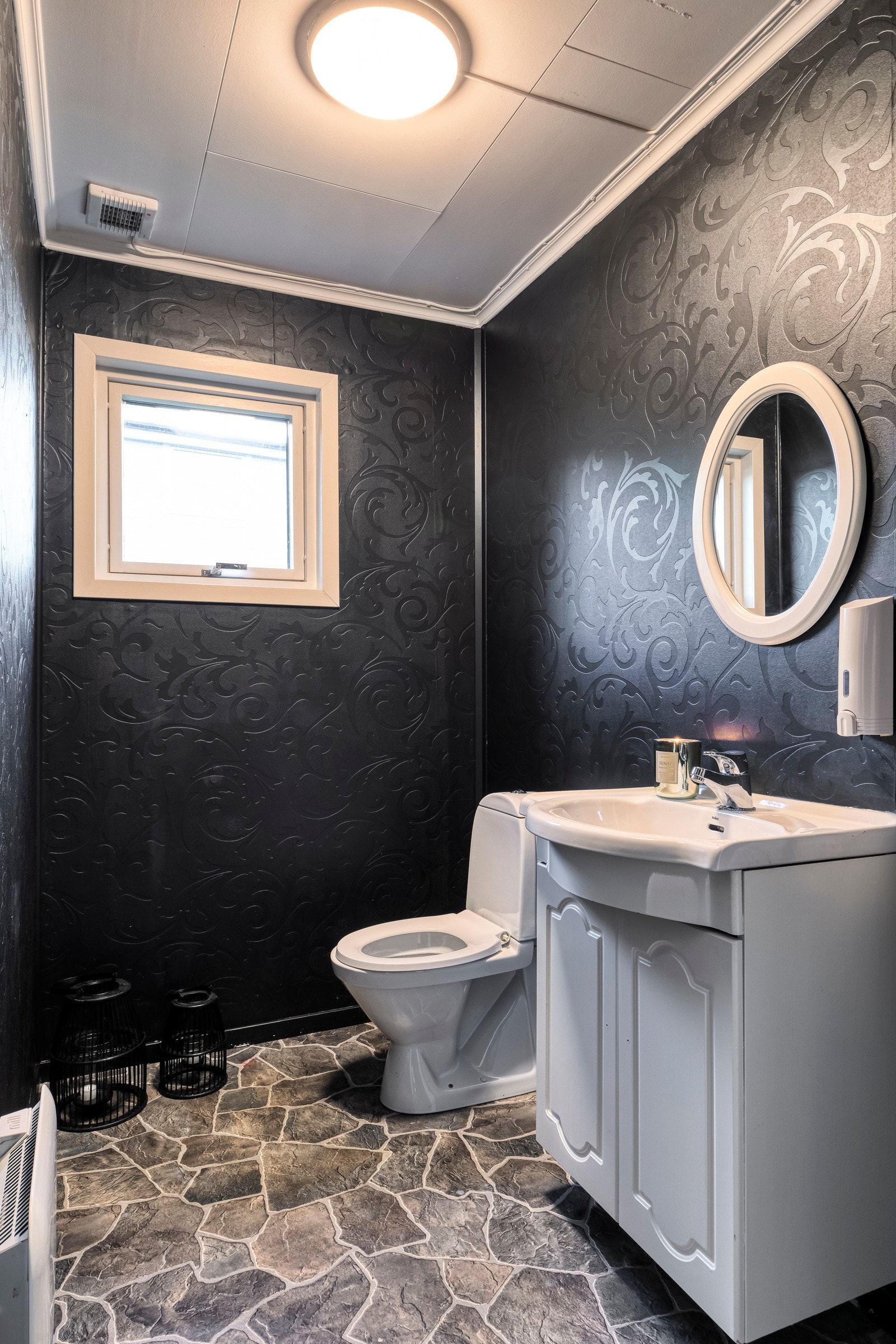 Praktisk toalettrom med skapseksjon med helstøpt servant og toalett. Galleribilde