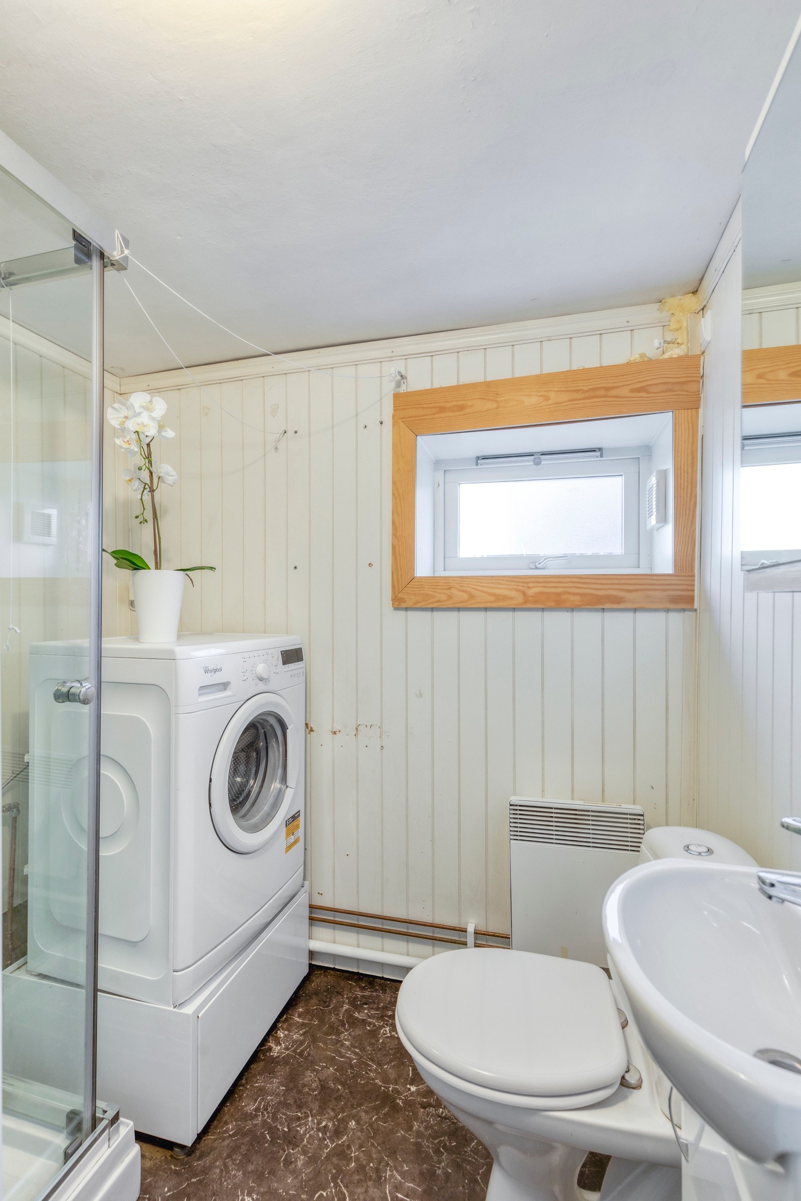 Det ene badet er av eldre årgang og består av dusjkabinett, toalett, servant med skap og opplegg for vaskemaskin. Galleribilde