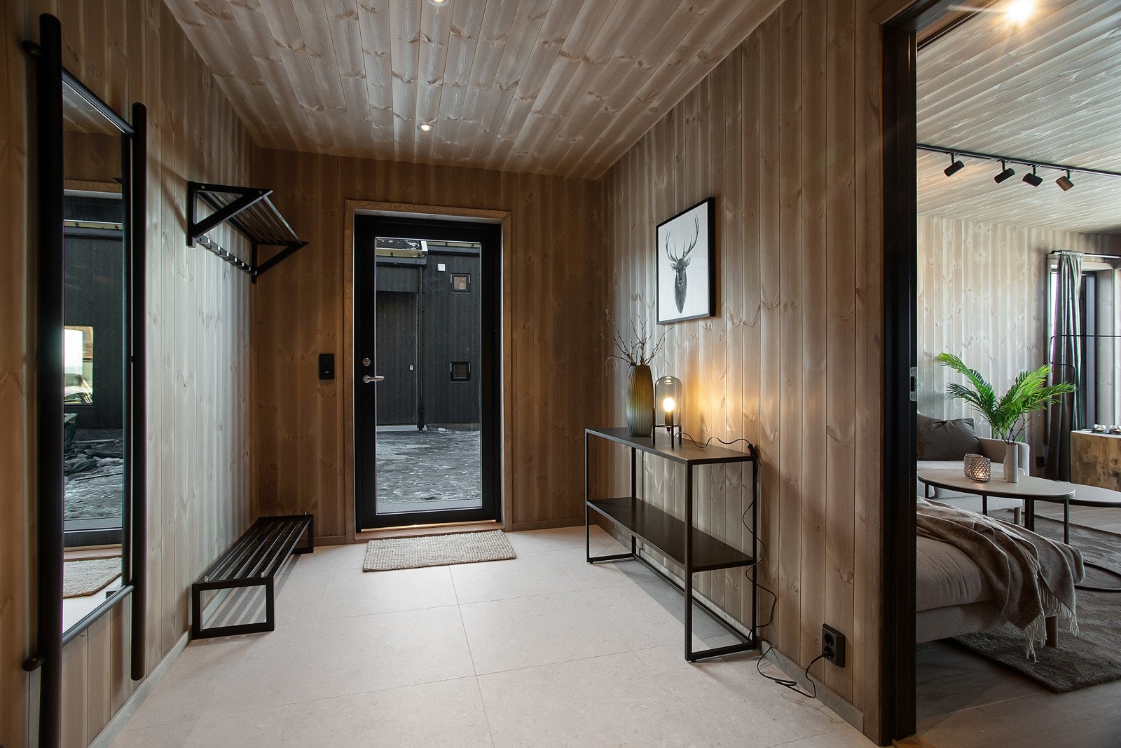 Innbydende og lekker entré med storformat-fliser og downlights i himling. Alle gulv i 1 etasje har varmekabler der stue, kjøkken og bad har wifistyring for å kunne sette hytta varm før ankomst. Galleribilde