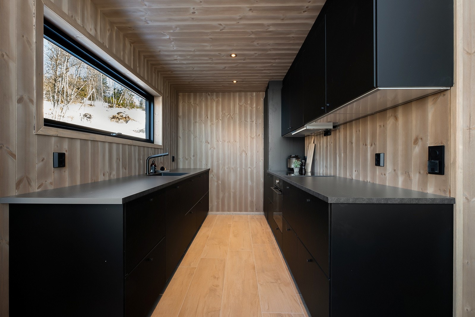 Moderne kjøkkeninnredning i sort utførelse og slette fronter som skaper et stramt og tidsriktig uttrykk. Galleribilde