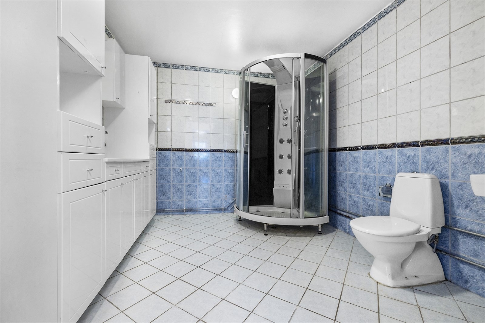 Badet inneholder dusjkabinett, wc, servantskap med ett-greps blandebatteri, speil på vegg, belysning og opplegg for vaskemaskin. Separat servant ved toalett Galleribilde