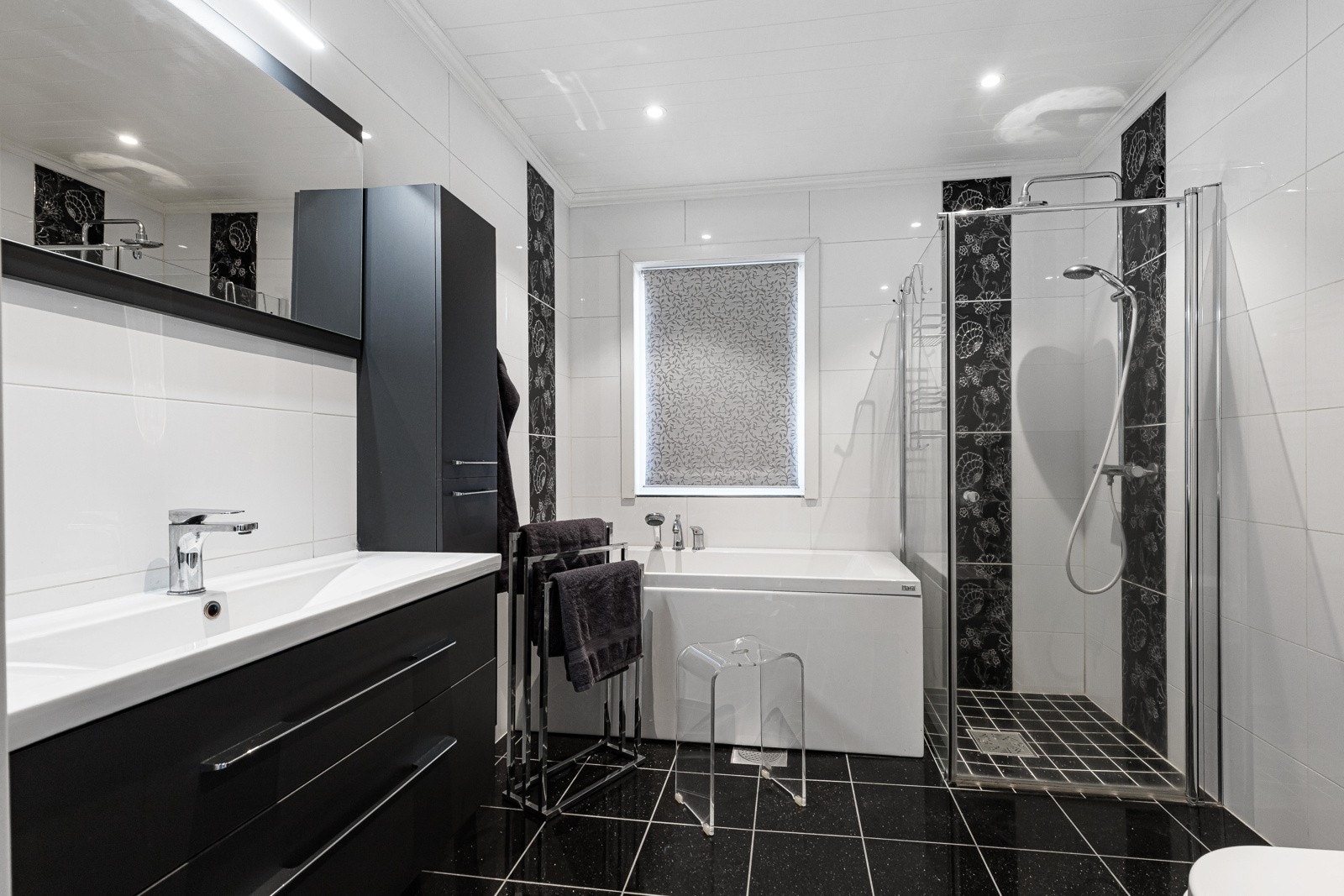 Badet ble renovert i 2016 og har panel med downlights i himling, granitt fliser på gulv og hovedsakelig hvite fliser med dekorfliser på vegg Galleribilde