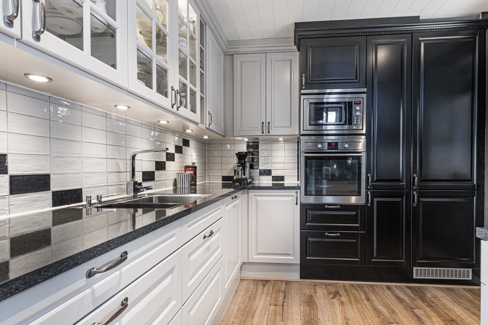 Videre er det fliser over benk, lys under overskap og laminerte benkeplater med kum av metall. Galleribilde