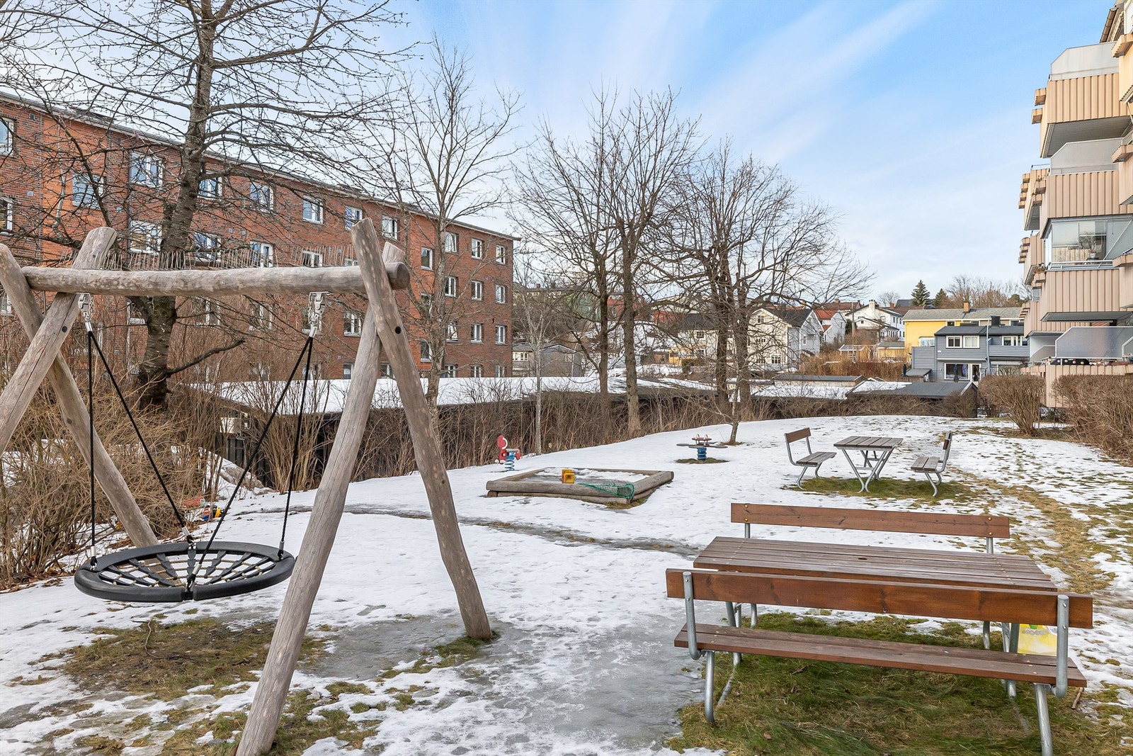 På forsiden av blokken er det lekestativ og benker. Her møtes store og små, med både to og fire bein, til lek og en kaffekopp Galleribilde