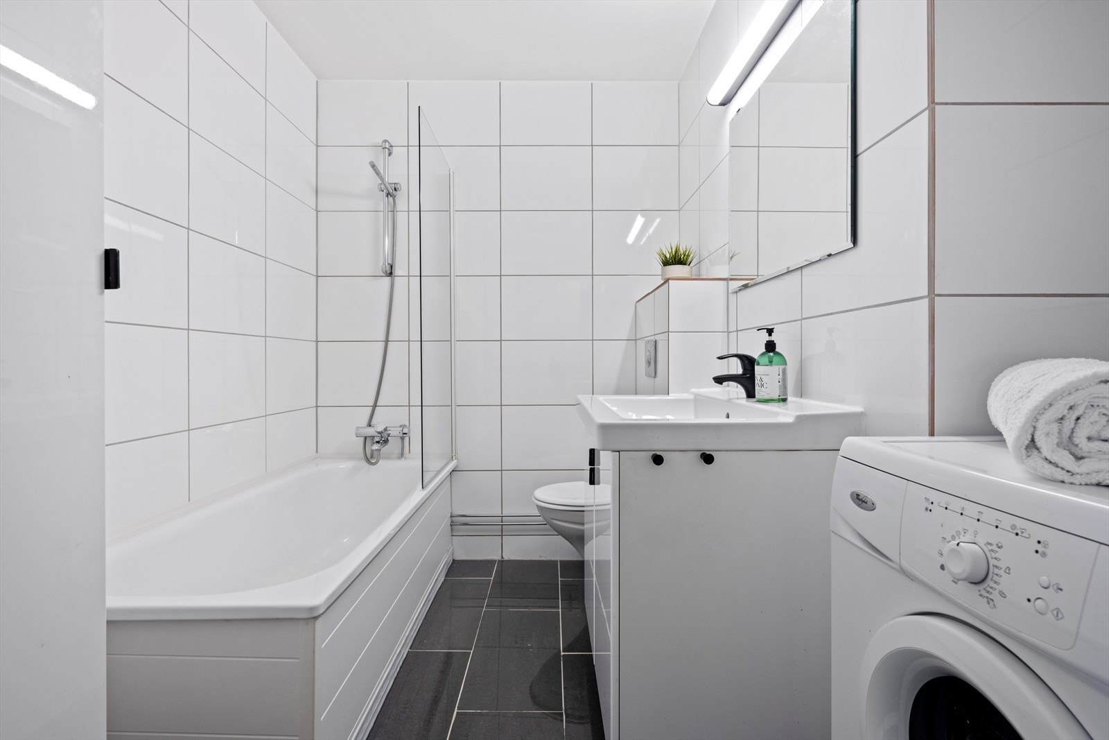 Baderommet er inndredet med koksgrå fliser over varmekabler på gulv og lyse fliser på vegger. Baderommet har fått kosmetiske forbedringer. Galleribilde