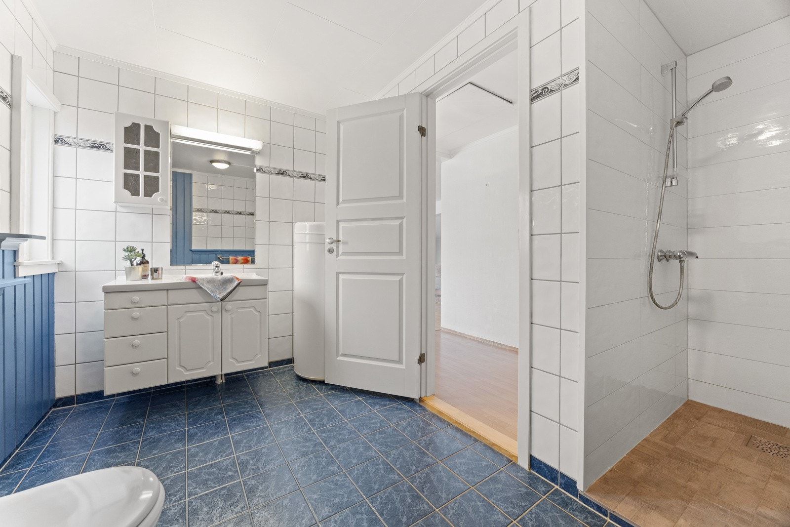 Eldre baderom innredet med dusjnisje, toalett, servant og opplegg for vaskemaskin. Galleribilde