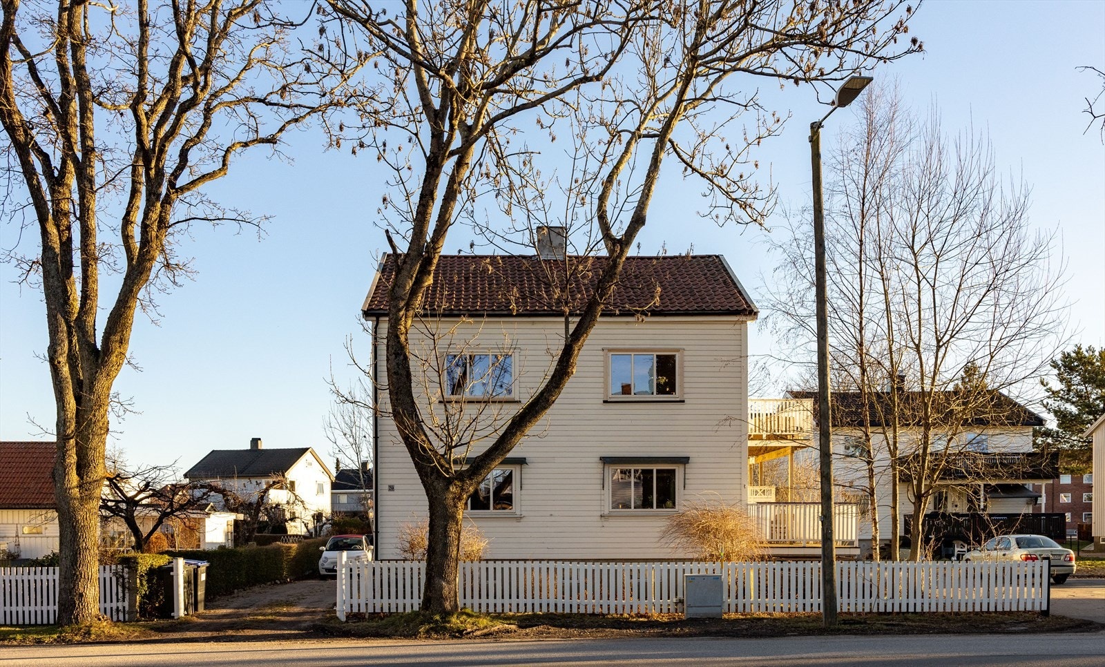 To flotte trær står på hver sin side av porten inn til eiendommen. Innkjørselen er gruset og romslig nok til flere biler. Galleribilde