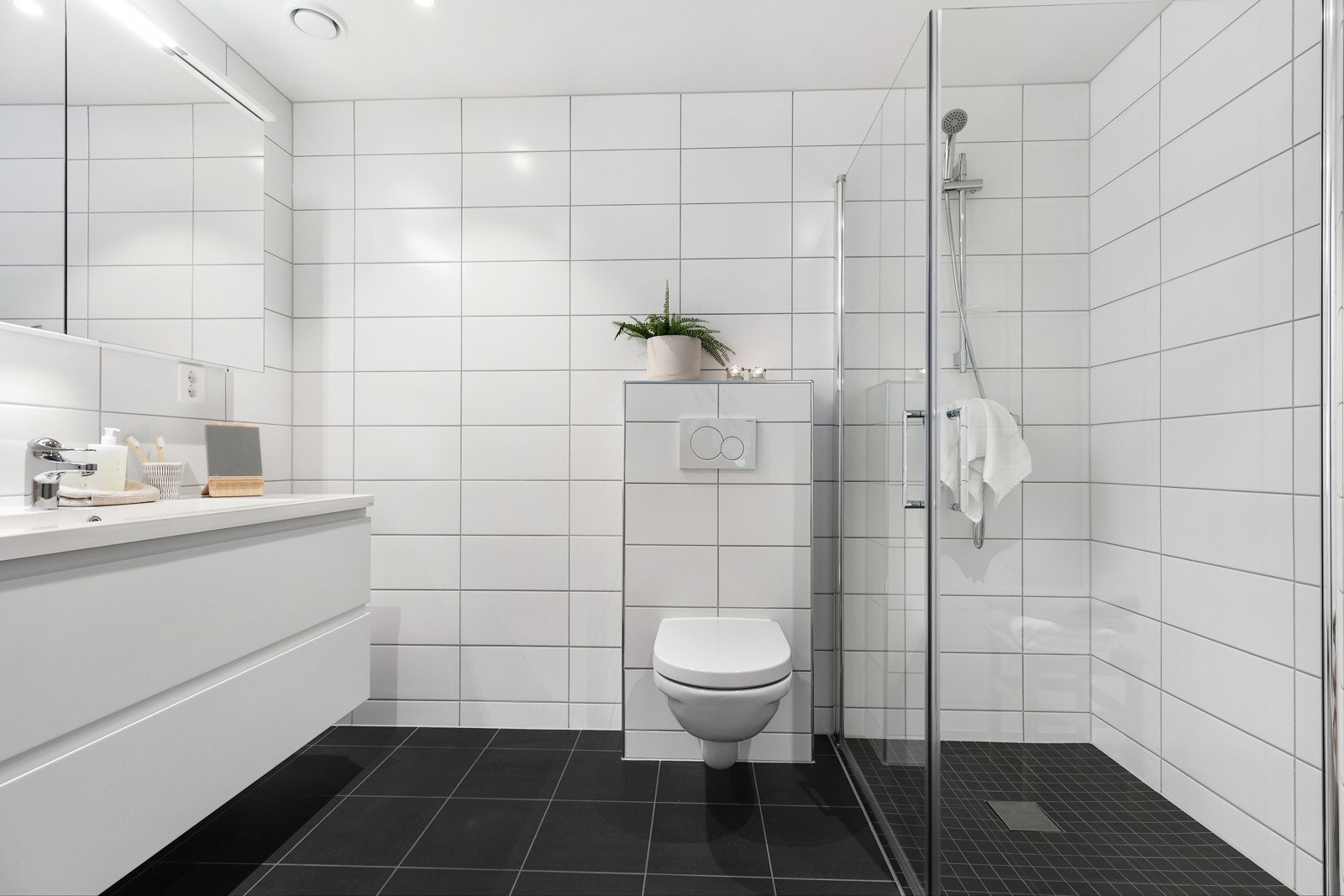 Dusjbadet ved hovedsoverom har dusjsone, vegghengt toalett og oppbevaringskapasitet i speilskap og servantseksjon Galleribilde