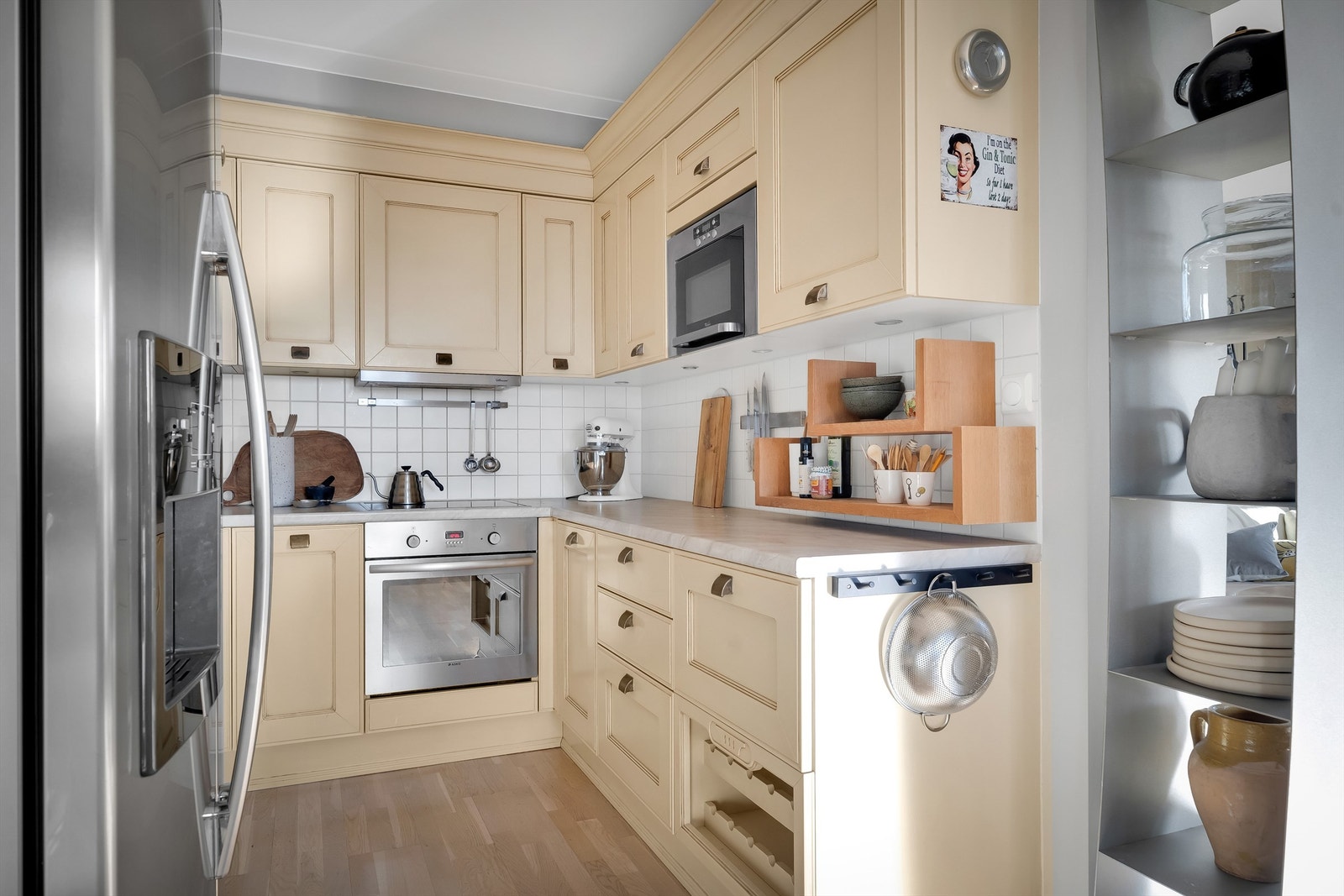 Kjøkkeninnredning i profilerte fronter og laminert benkeplate. Overskap med overskapsbelysning og stikkontakter på vegg over benkeplate. Galleribilde