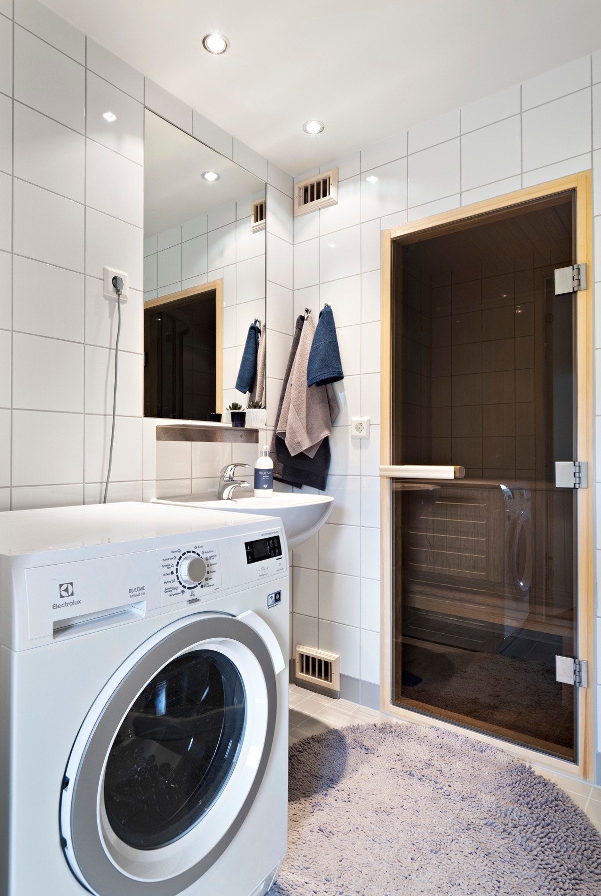 Servanten er vegghengt og over er det et innfliset speil. Videre har badet dusjhjørne, vegghengt toalett og opplegg for vaskemaskin. Badet er tilknyttet ventilasjonsanlegget. Galleribilde