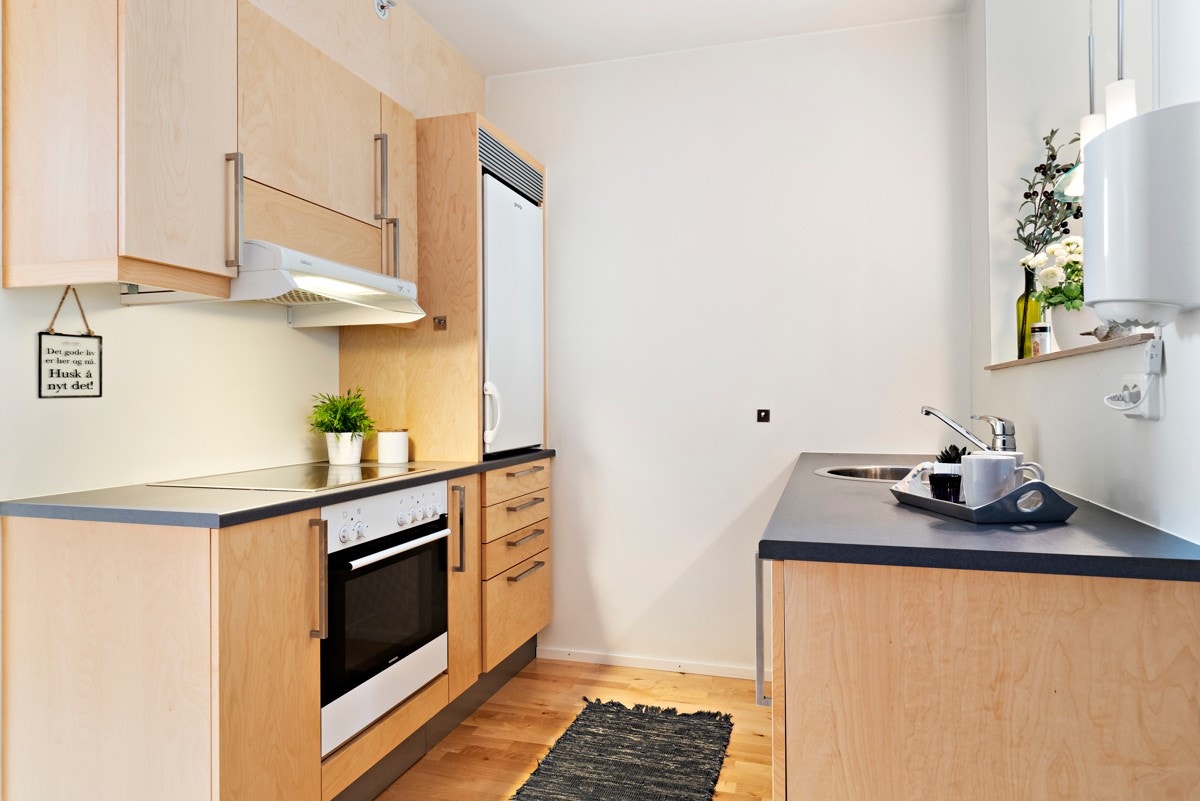 Kjøkkenet ligger smart plassert mellom stuen og spisestue. Arbeidssonen er godt skjermet, selv om det er en stor åpning mot stuen over den ene kjøkkenbenken. Galleribilde