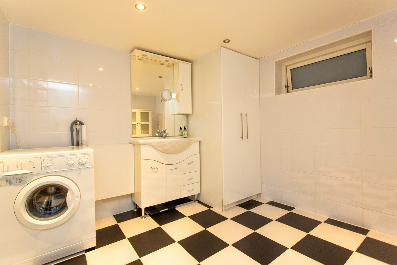 Romslig og oppusset bad/vaskerom med varmekabler og flis på gulv (Utleiedel) Galleribilde