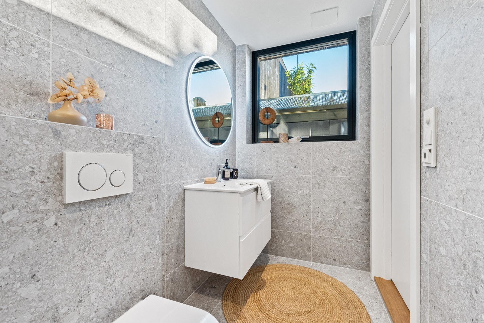Dette badet er innredet med servant med skuffer under, vegghengt toalett og dusjhjørne med innfellbare glassdører. Galleribilde