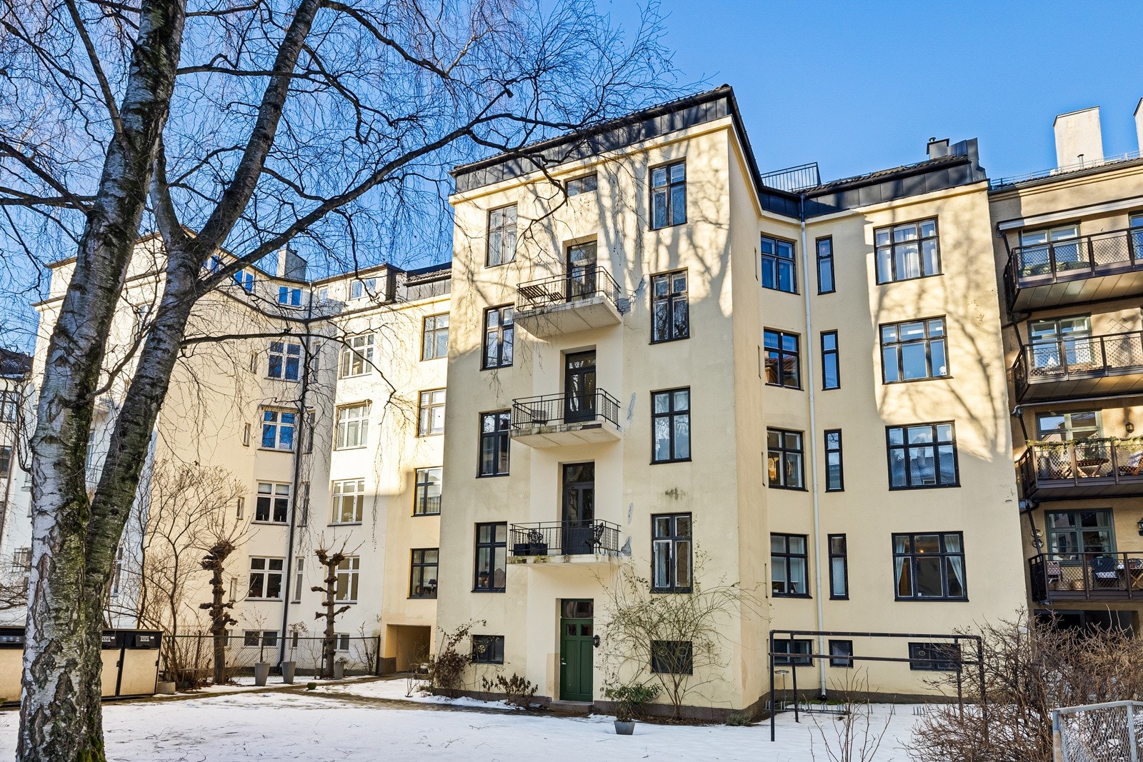 Pent opparbeidet bakgård med sittegruppe og have med plen, bed, busker og trær. Beplantet forhave mot gate. Parti med brostein fra fortau til inngangsdør. Galleribilde