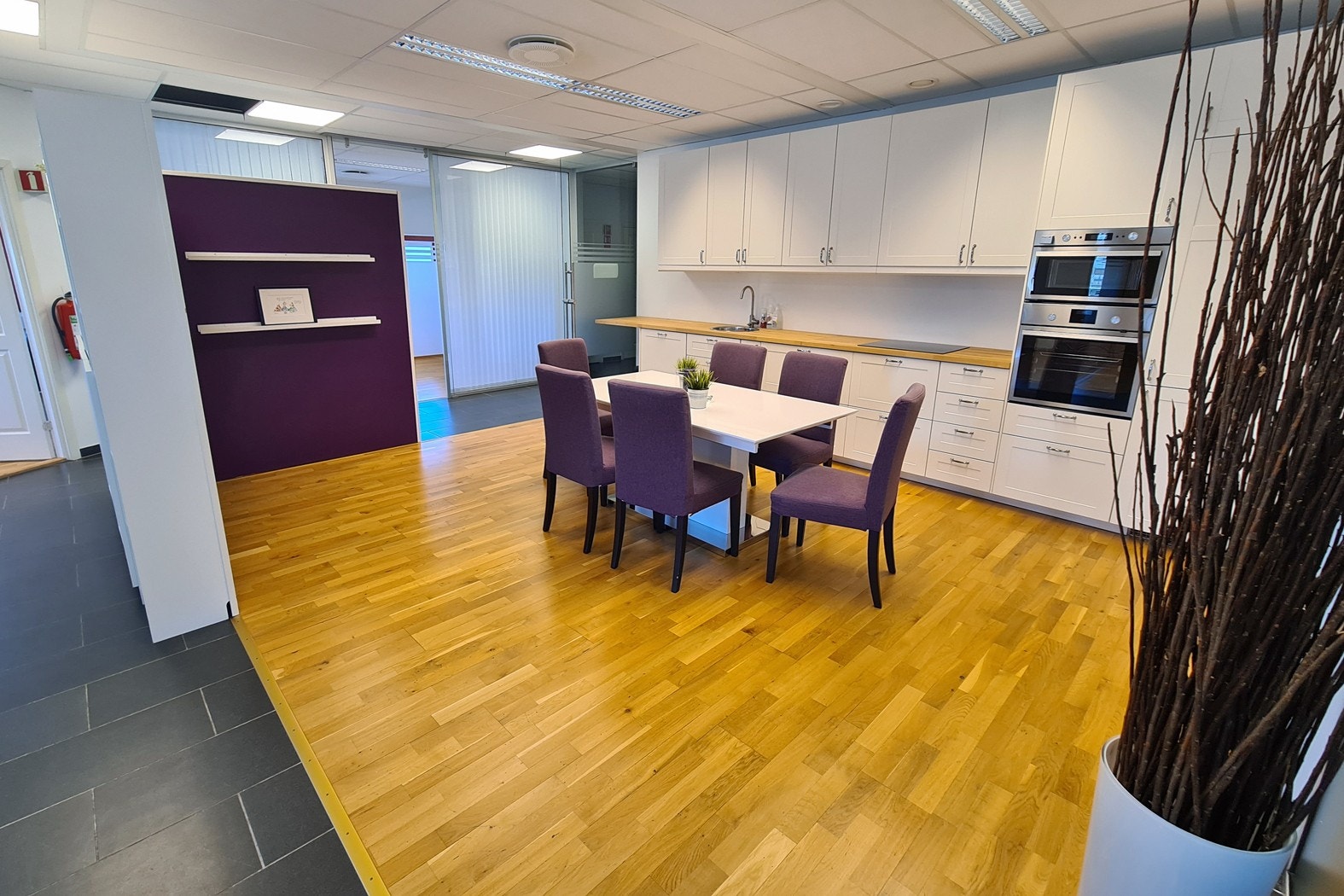 Kjøkken i nøytrale farger, med profilerte fronter. Et samlingspunkt midt i "kontorlandskapet". Galleribilde