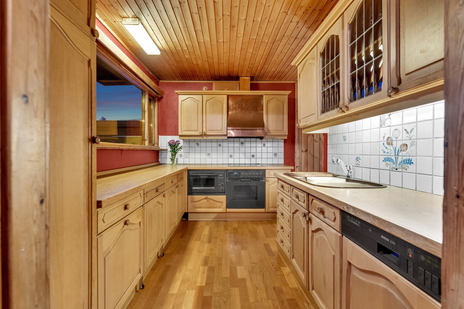 Over benken er veggen beskyttet med hvite fliser som står godt til resten av interiøret. Videre er kjøkkenet utstyrt med integrerte hvitevarer som oppvaskmaskin, kjøleskap, mikro, stekeovn og koketopp, samt ventilator, benkebelysning og benkestikk Galleribilde