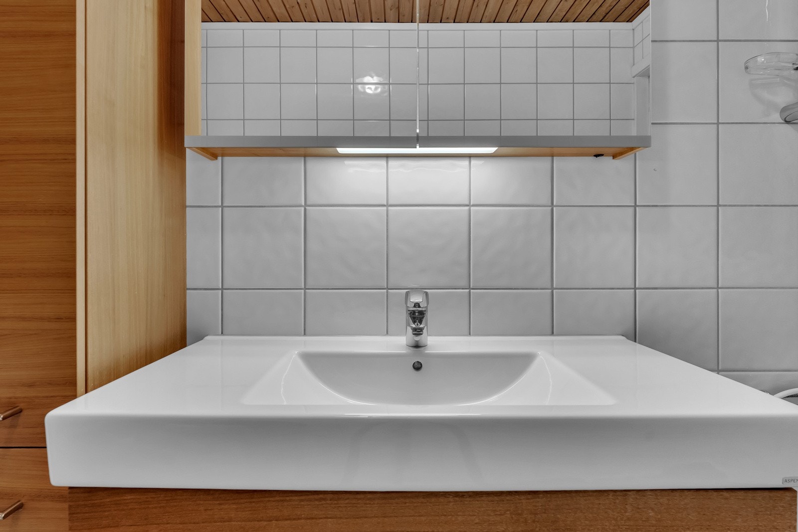 Her er det hvite fliser på veggene, naturlig panel i himlingen og mørkegrå fliser på gulv med gulvvarme Galleribilde