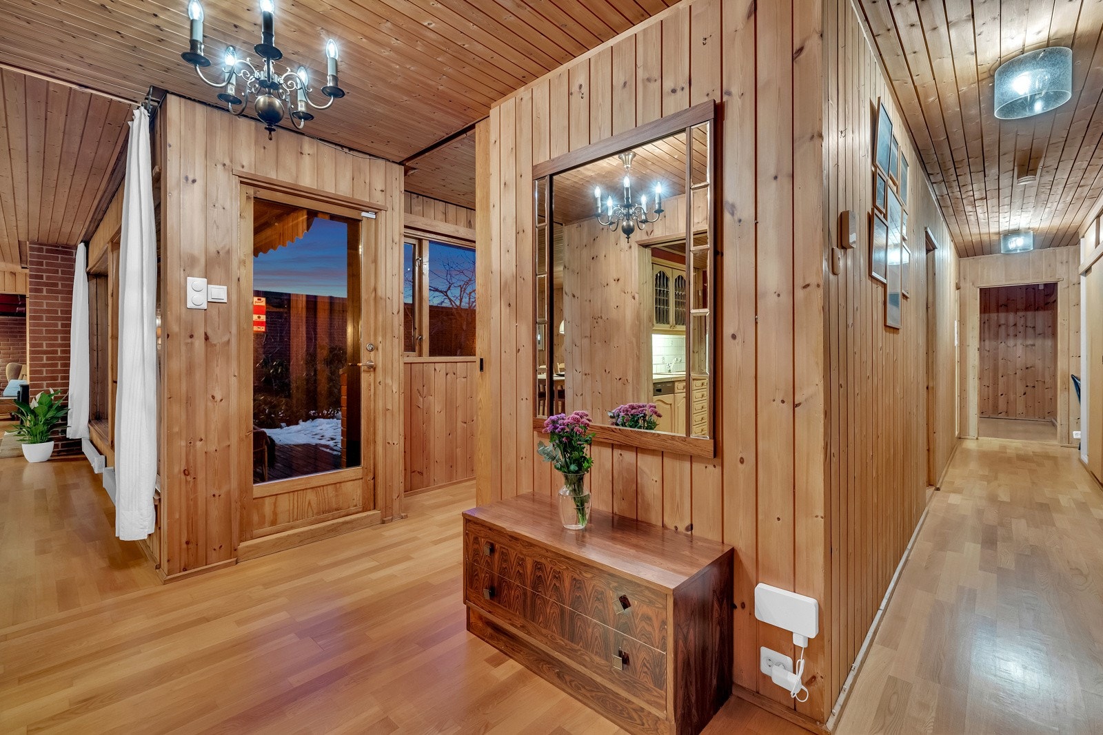 Vel inne er det et lite vindfang, og neste rom er en langstrakt, romslig gang med panel på veggene og gyllen parkett på gulvet. I gangen er det god oppbevaringsplass i en bred skyvedørsgarderobe, og i ruskevær kan tørkeskapet ved garderoben komme godt med Galleribilde