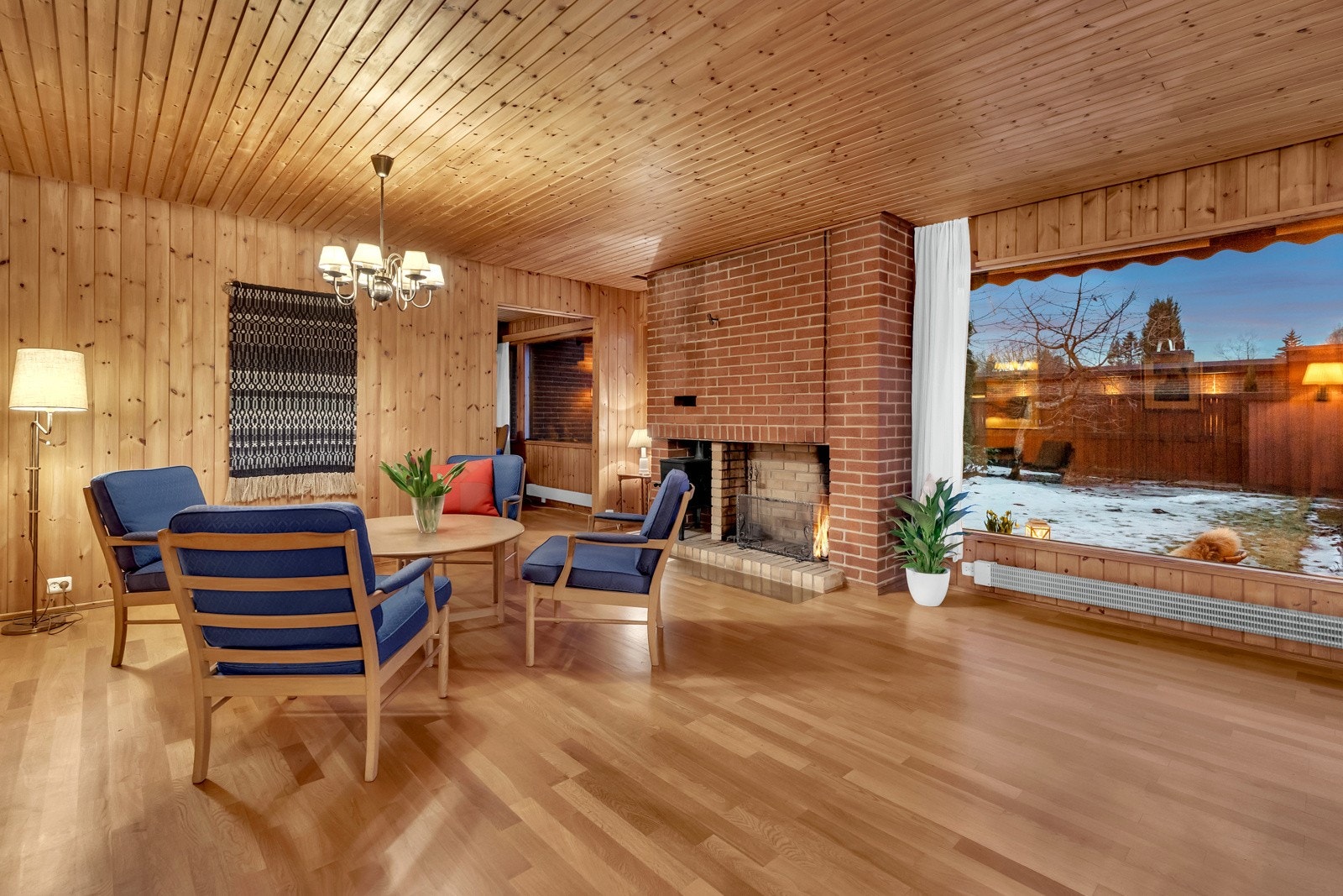 Stuen har store vindusflater, naturlig panel på veggene og gyllen parkett på gulvet. Galleribilde