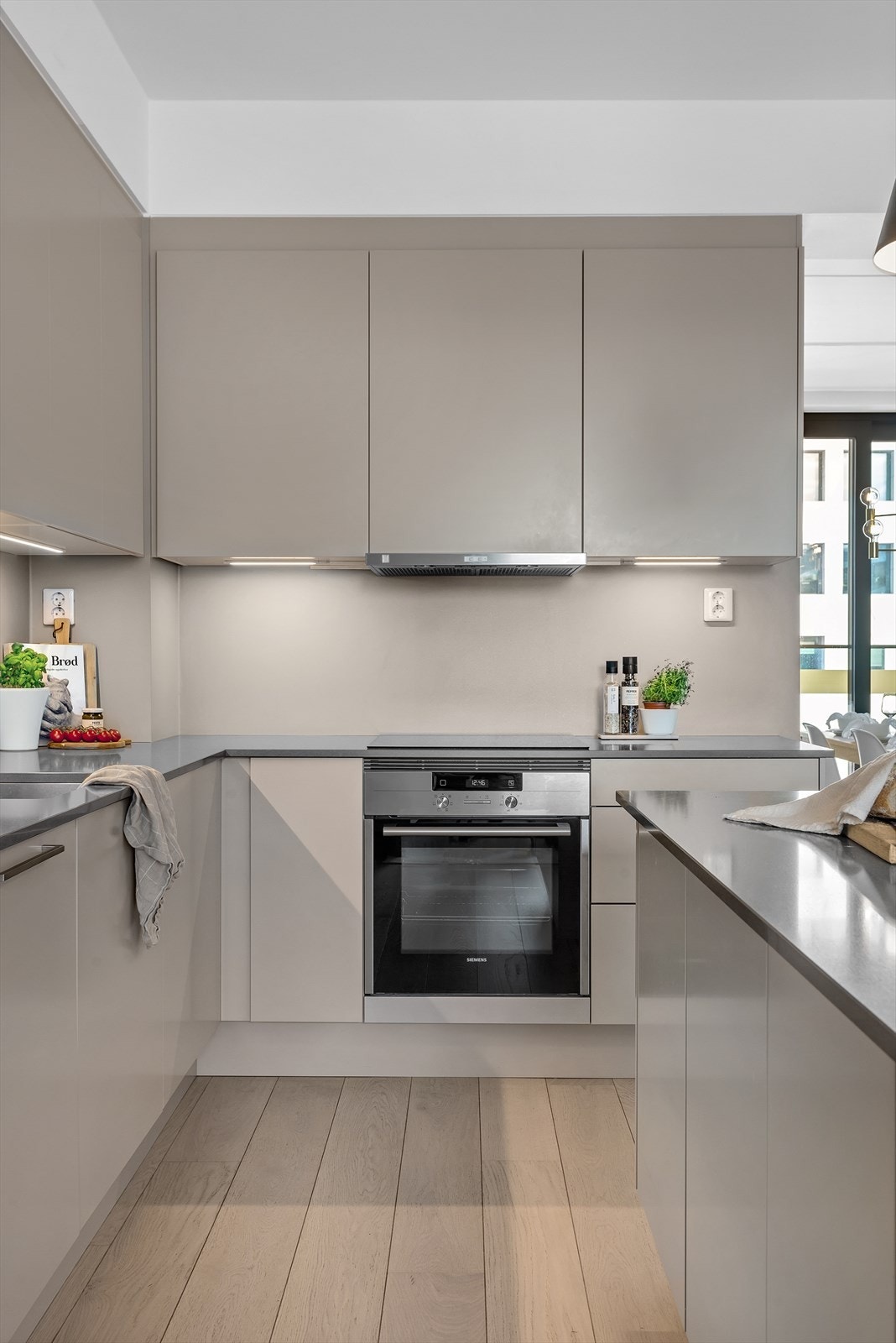 Delikat kjøkkeninnredning fra Sigdal med slette beige fronter og kompositt benkeplate med nedfelt benkebeslag Galleribilde