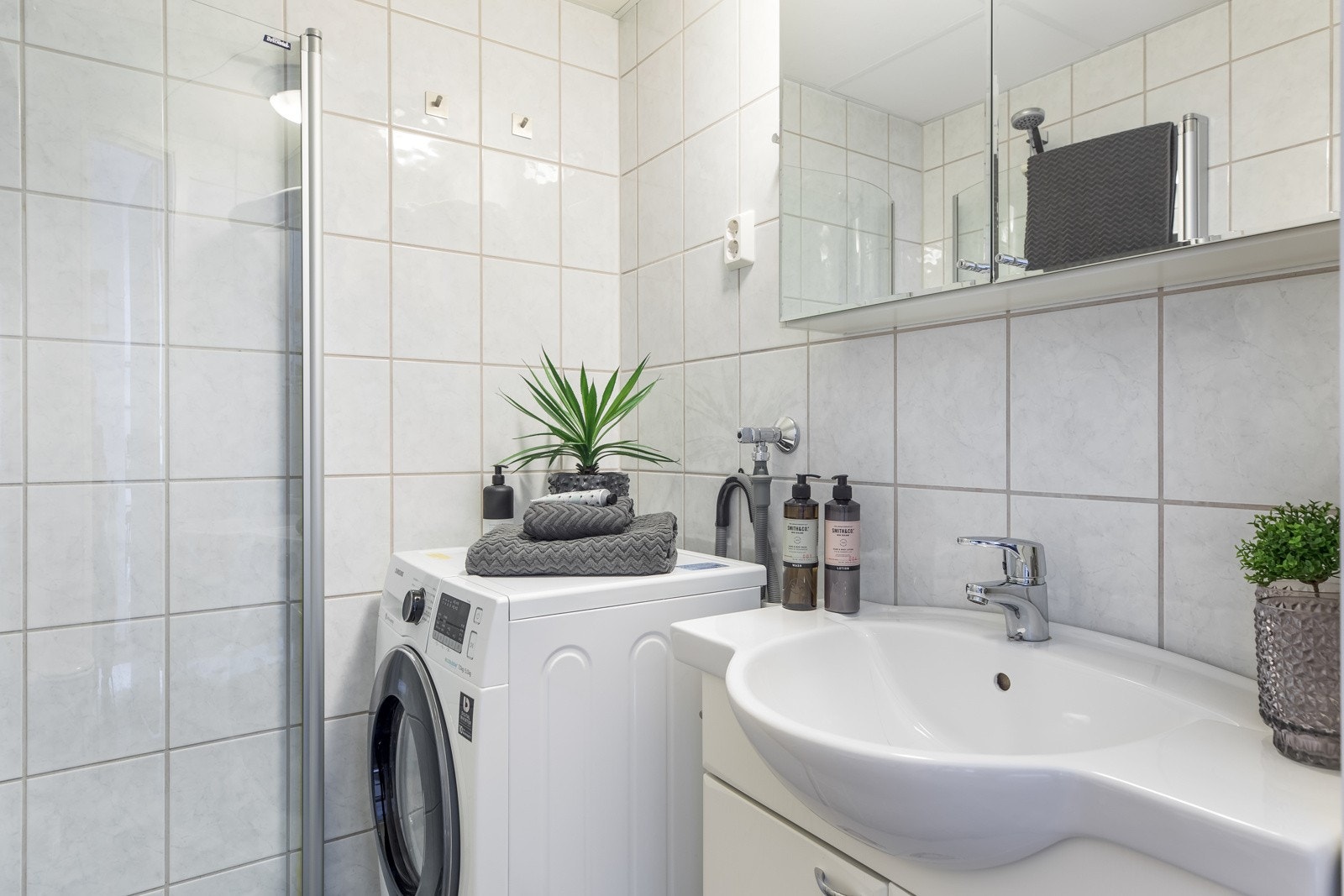 På det flislagte badet finner du innfellbare dusjdører, veggmontert wc og opplegg for vaskemaskin Galleribilde