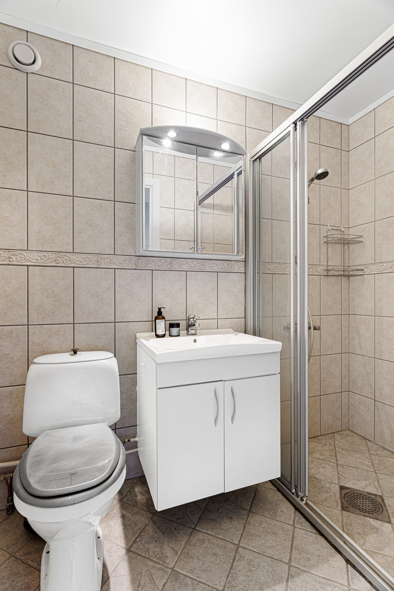 Badet er av eldre dato, men gir et fint inntrykk med flislagte overflater, varmekabler, toalett, og dusjhjørne med skyvedør. Galleribilde