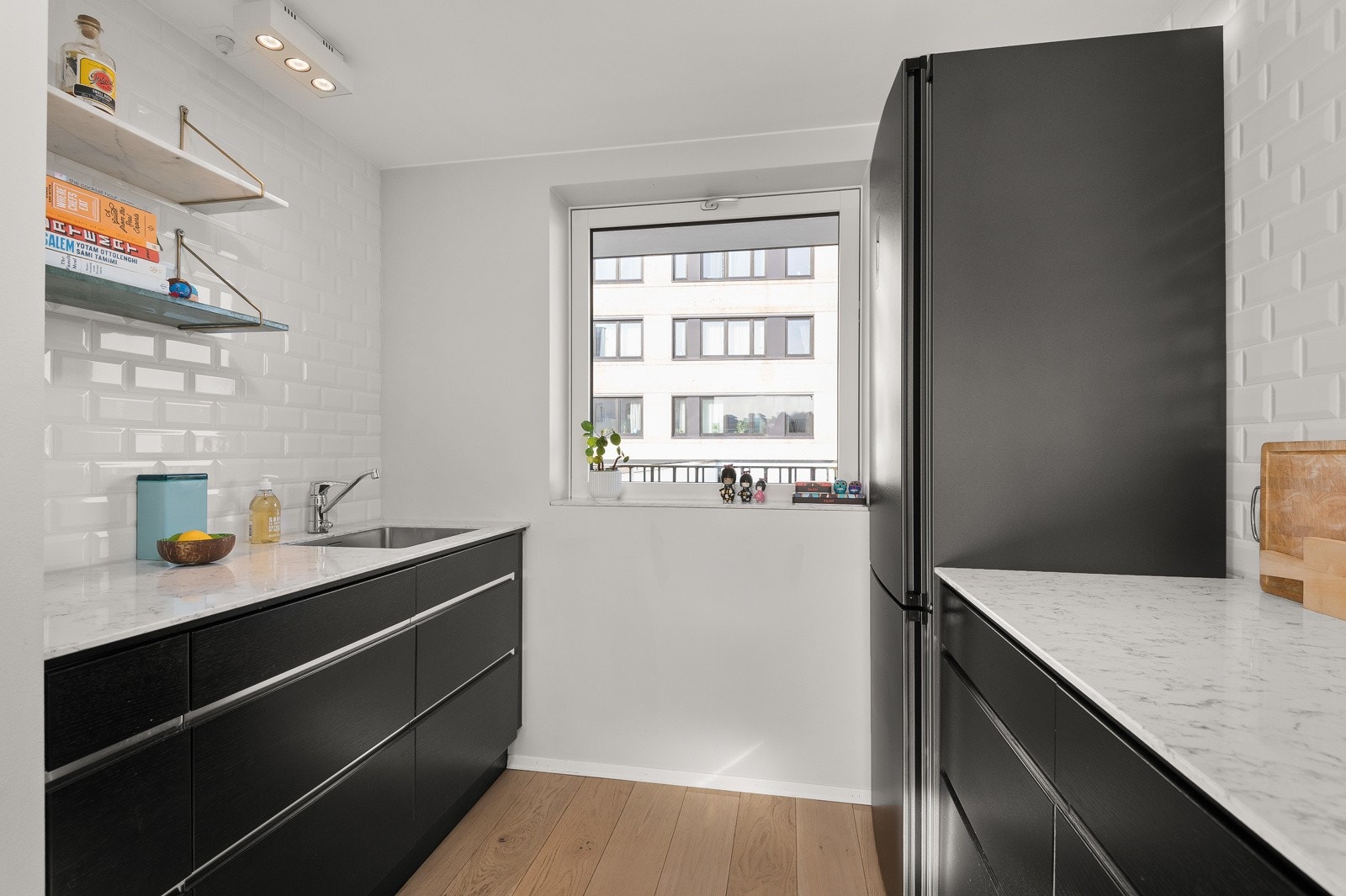 Kjøkkenet har slette mørke fronter og benkeplater av kompositt materiale Galleribilde