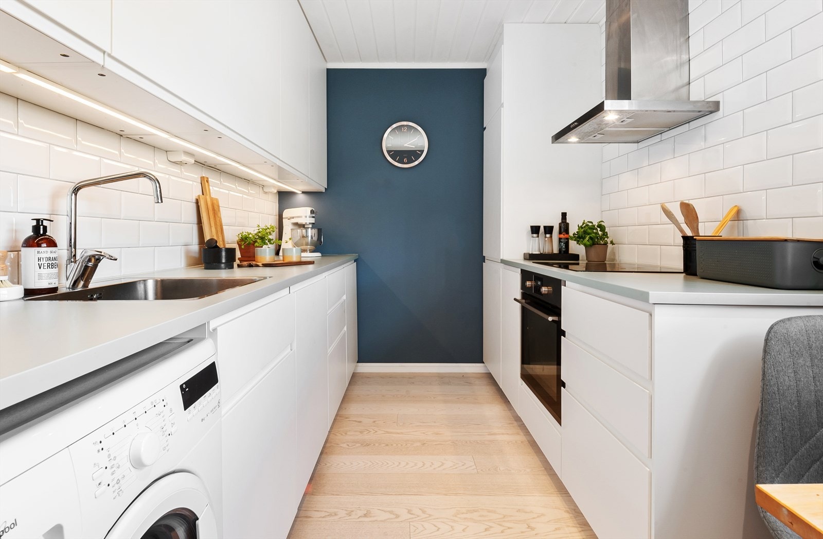 Kjøkken fra 2016/2017 med hvite, folierte og glatte fronter, fliser over benk og benkeplate med underlimt vaskekum. Galleribilde