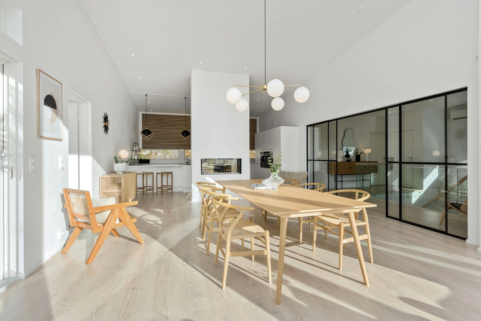 Spisestue og kjøkken er avdelt med gasspeis. Skyvedører i glass og svarte stålprofiler Galleribilde