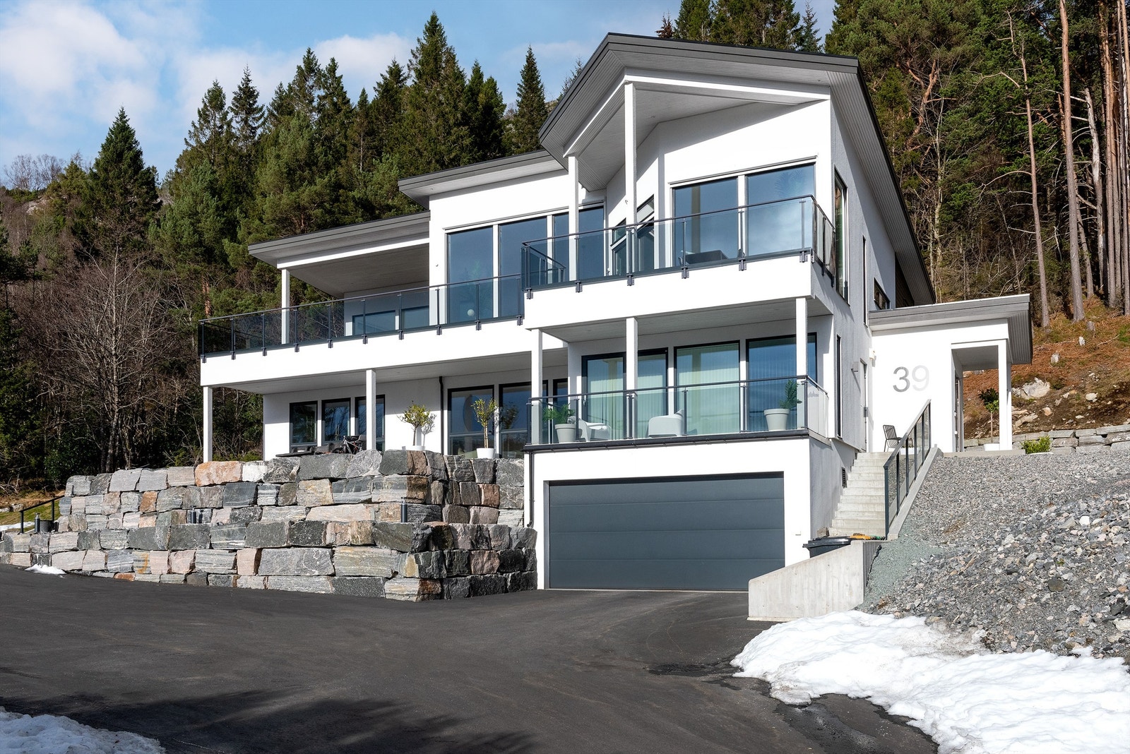 Flott fasade. Boligen ligger høyt og fritt og har rikelig med parkeringsareal og natursteinsmurer. Galleribilde