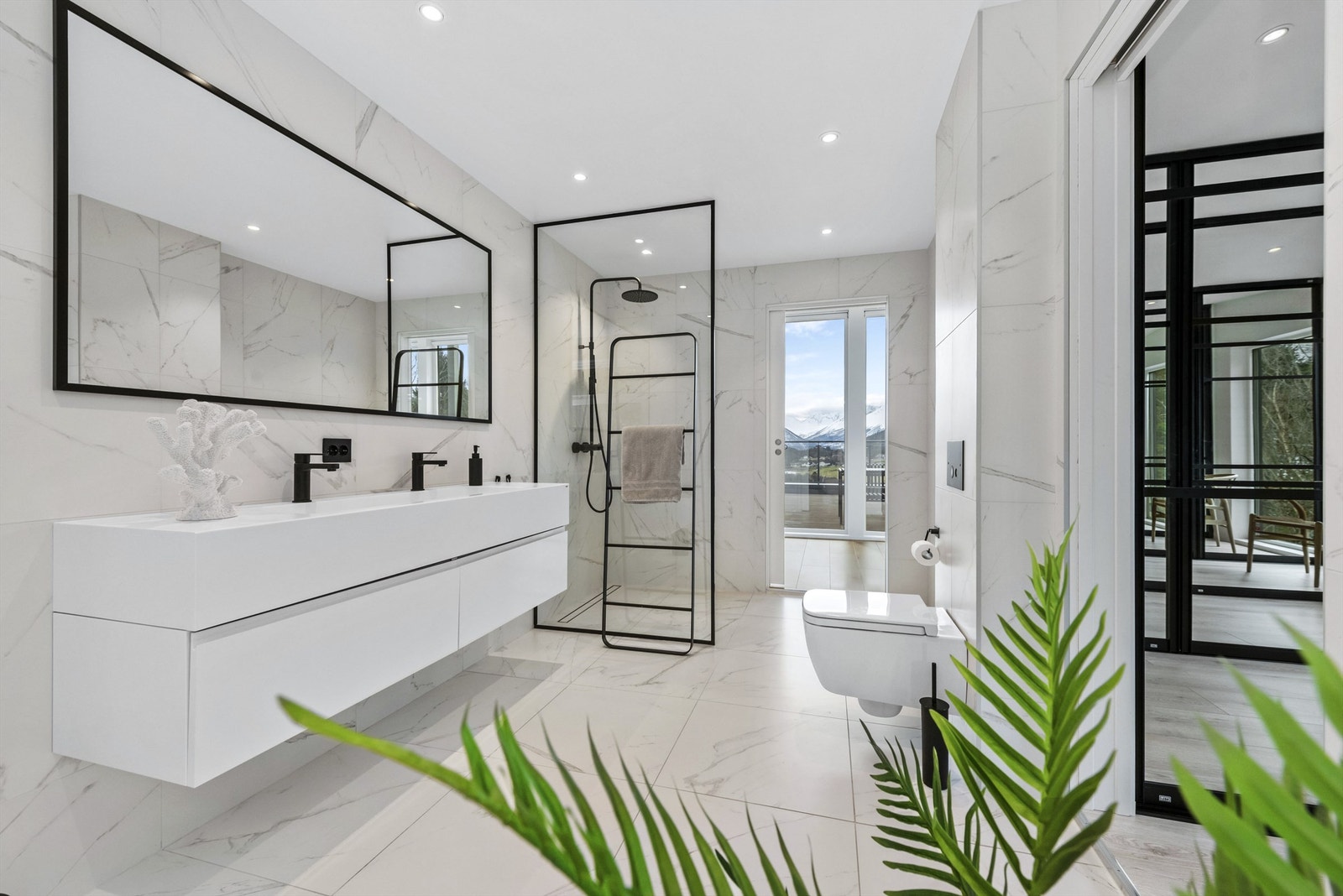 Lekkert flislagt bad i tilknytning til hovedsoverom. Det er 60 x 60 fliser i matt marmor på gulv og vegger. Dusjvegg og regndusj fra Tapwell. Innredning med dobbel servant og speil med svart ramme er limt på veggen. Ledspotter i tak. Galleribilde