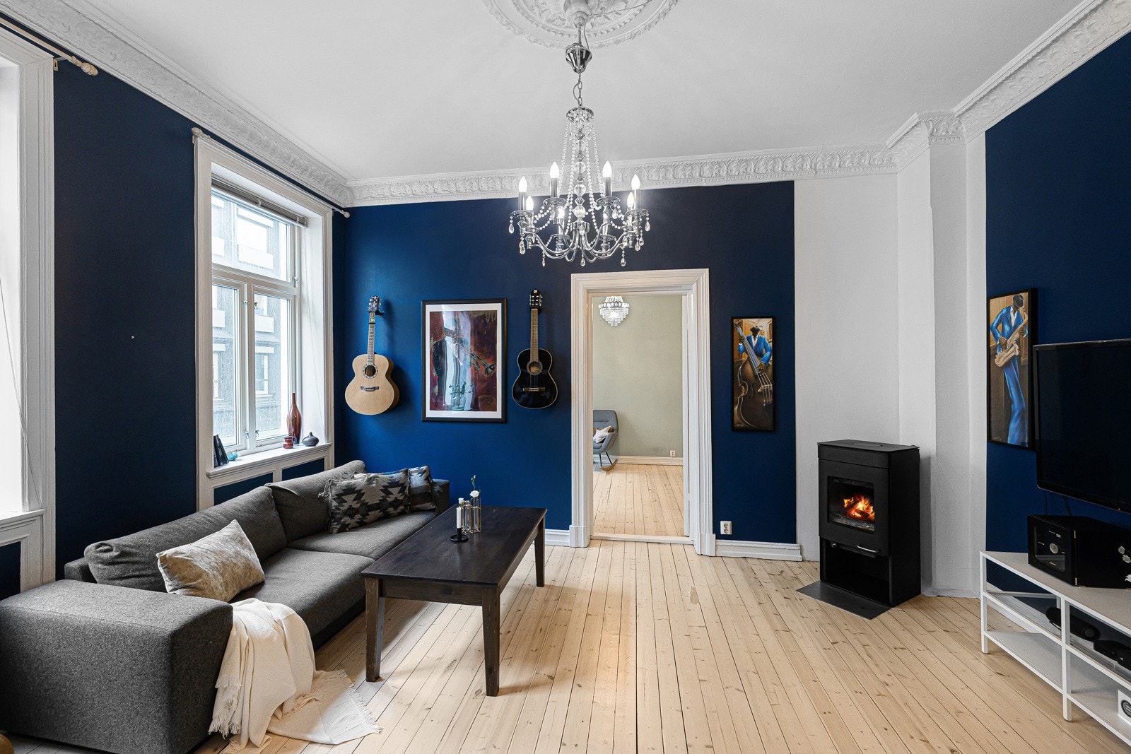 Leiligheten har en lys og trivelig stue med en koselig peisovn. Galleribilde