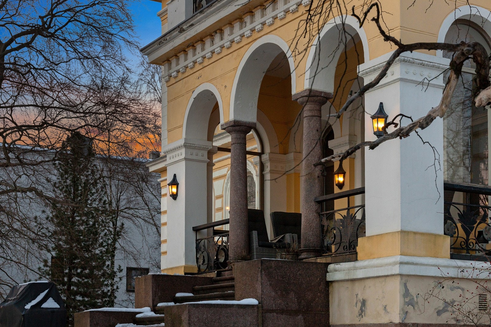 Terrassen i første etasje er overbygget av terrassen i andre etasje og har rekkverk i smijern med toppbeslag på håndløper i tre. I front av terrassen er det buede steinsøyler på hver side av en bred trapp ned til hagen. Galleribilde